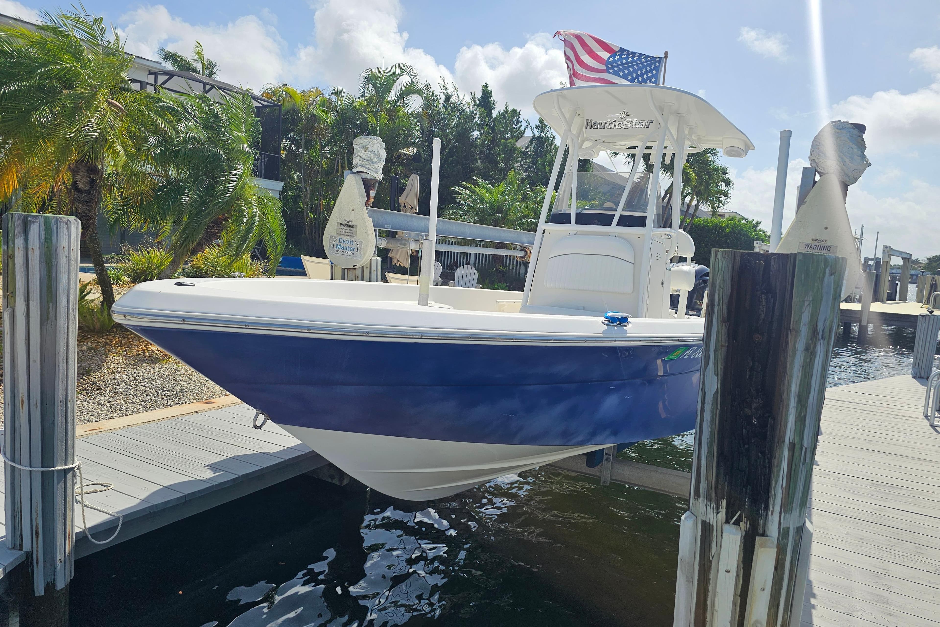 2014 NauticStar 244 XTS boat docked, featuring blue hull and American flag.