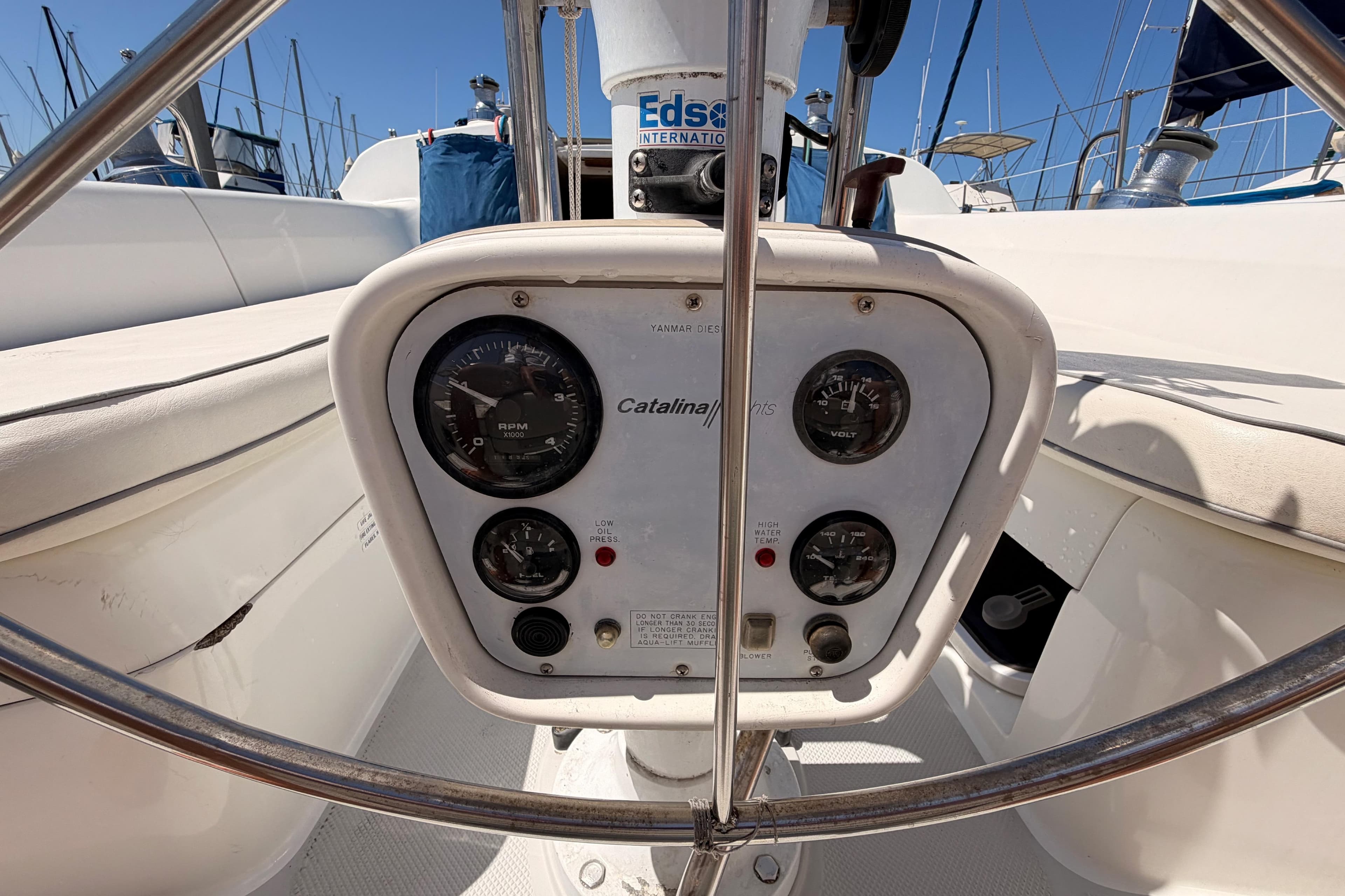 Cockpit controls of a 1999 Catalina 320 sailboat with gauges and steering wheel.