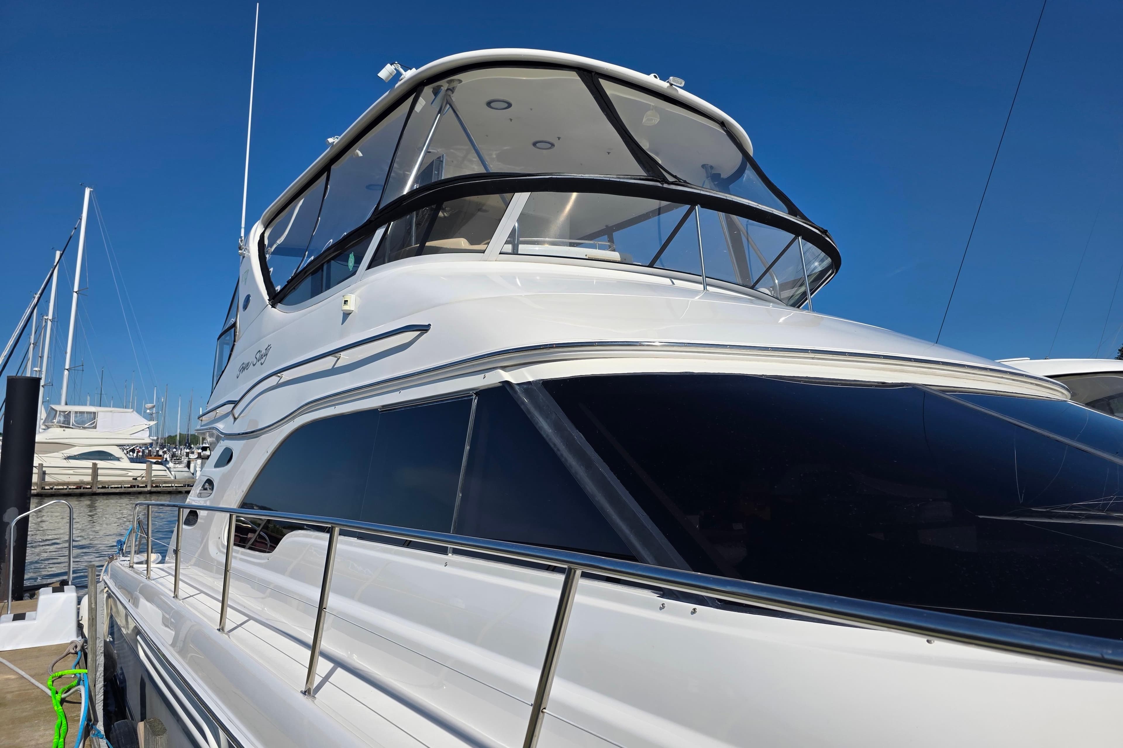 2002 Sea Ray 560 Sedan Bridge yacht docked at marina under clear blue sky.