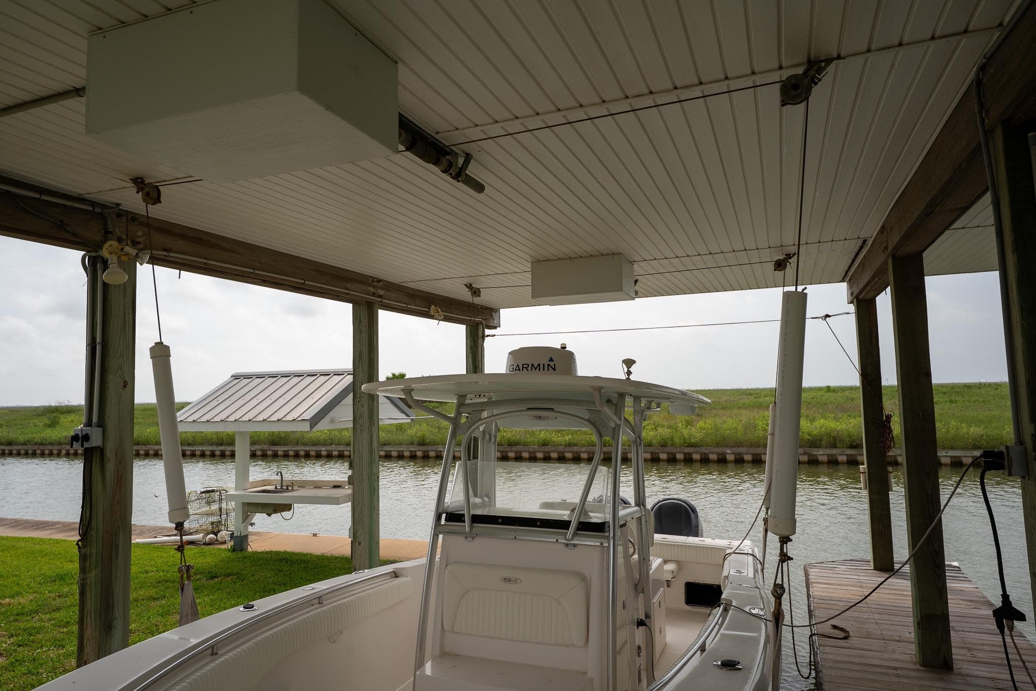 2007 Sea Hunt Triton 290 docked under covered boathouse by a canal.