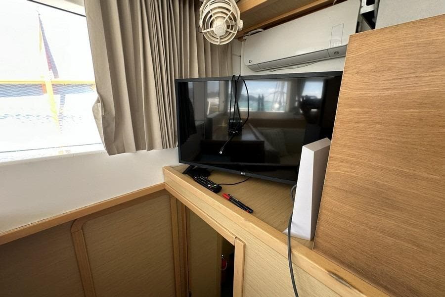 Interior of 2013 Lagoon 39 yacht with TV, remote, and wooden cabinetry.