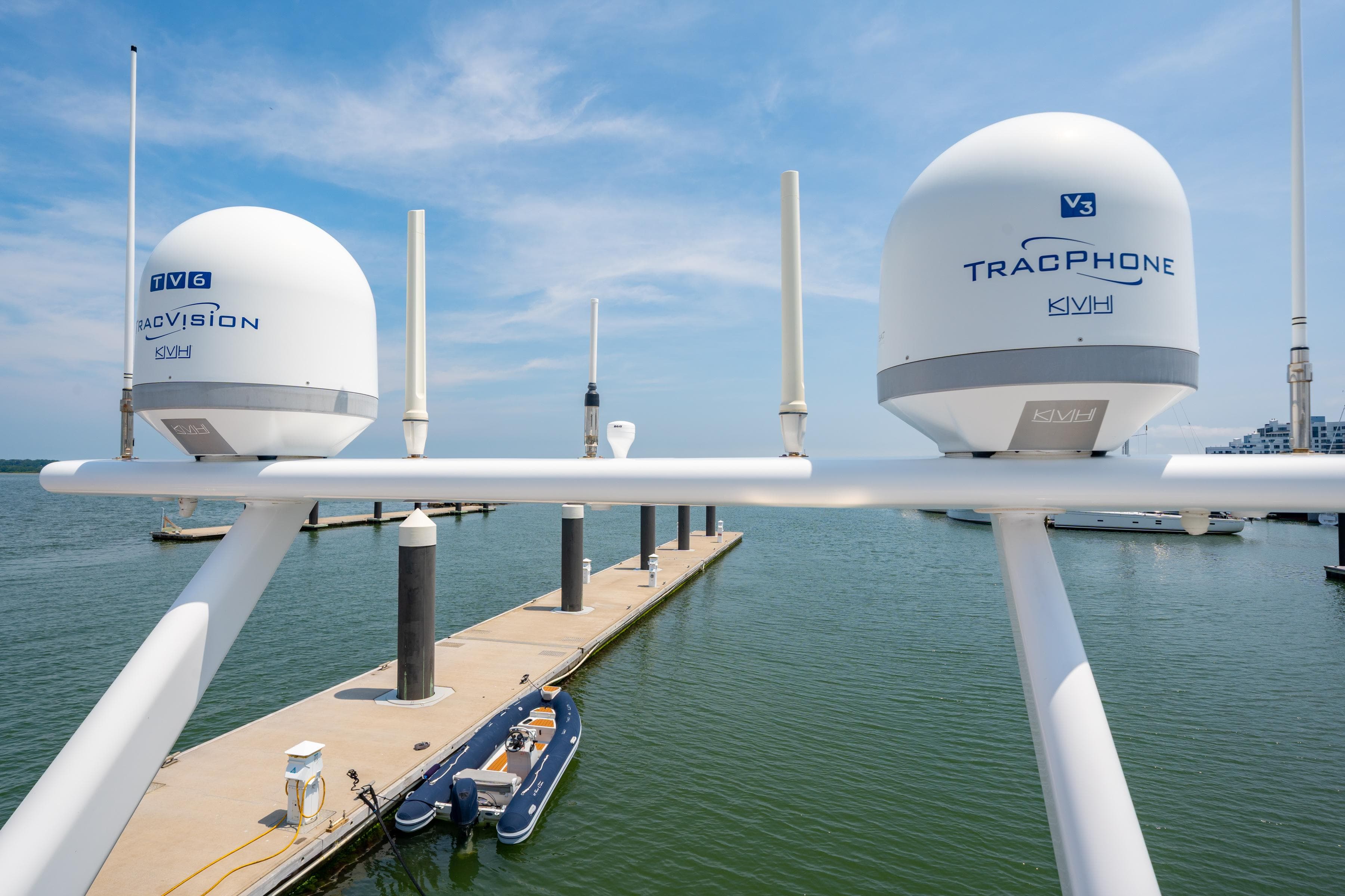 Satellite domes on a Privilege 745 yacht, docked at a marina, under a clear blue sky.