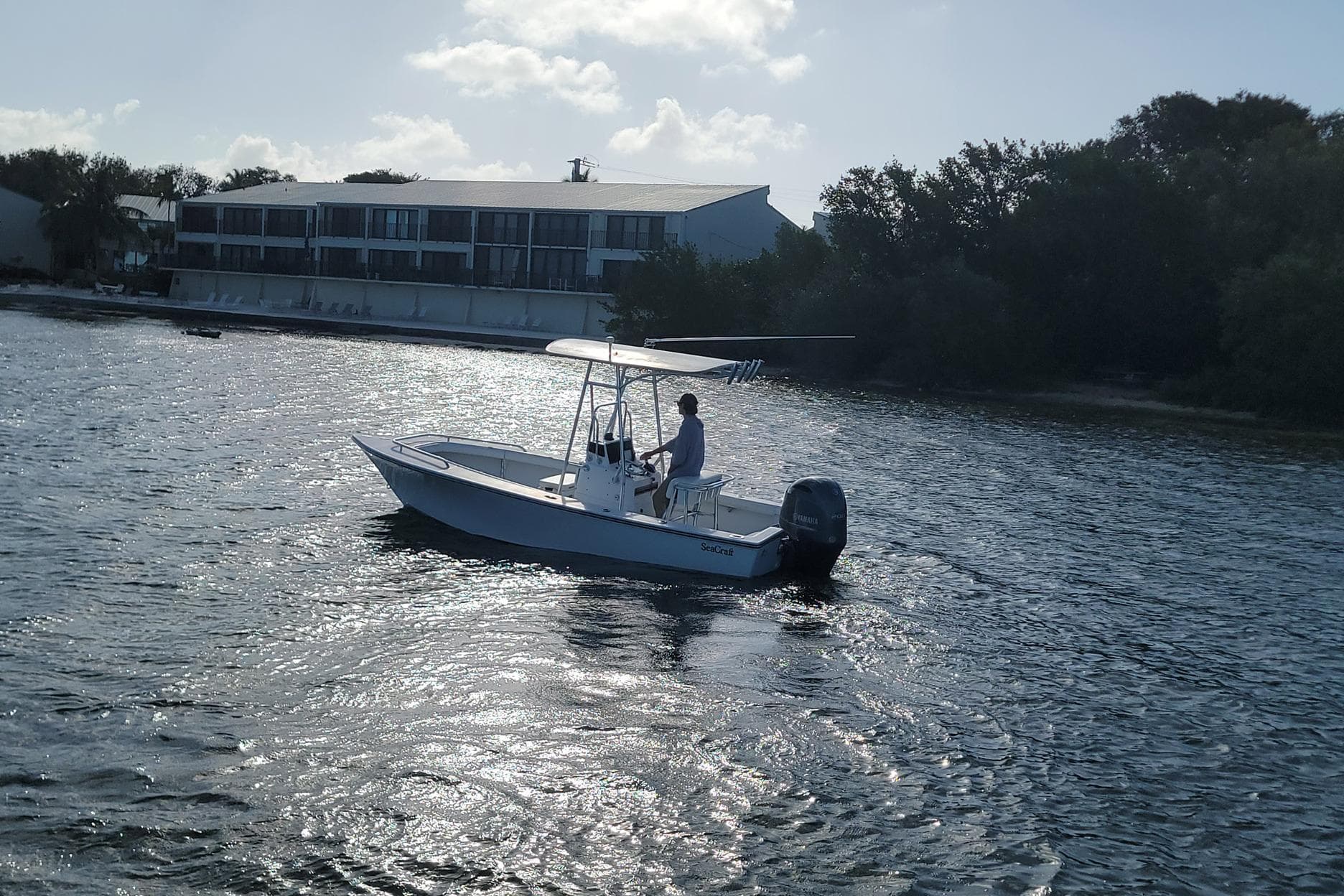 2008 SeaCraft SC 20 Classic boat cruising on a sunny day near a waterfront building.