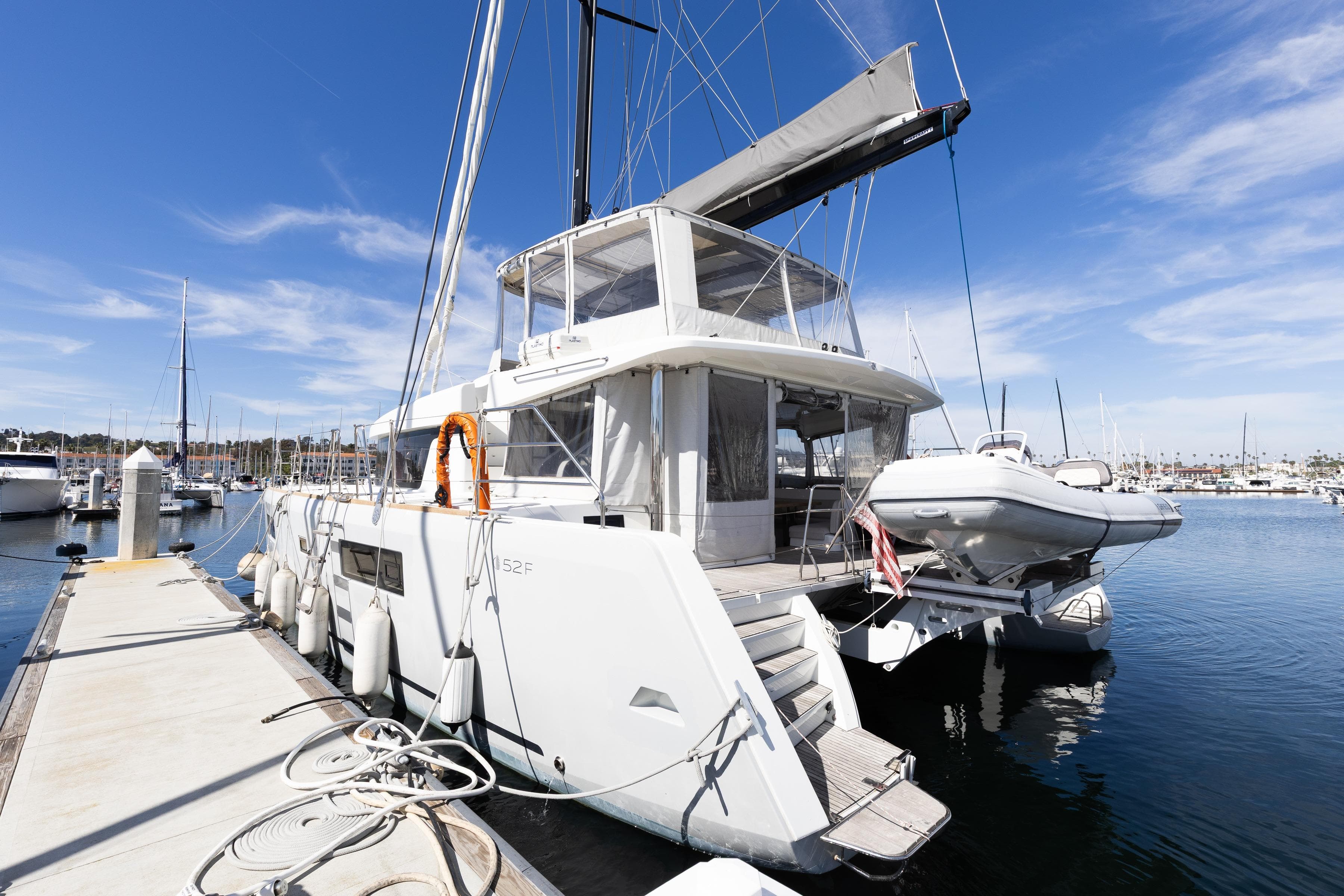 2022 Lagoon 52 F catamaran docked at marina under clear blue sky.
