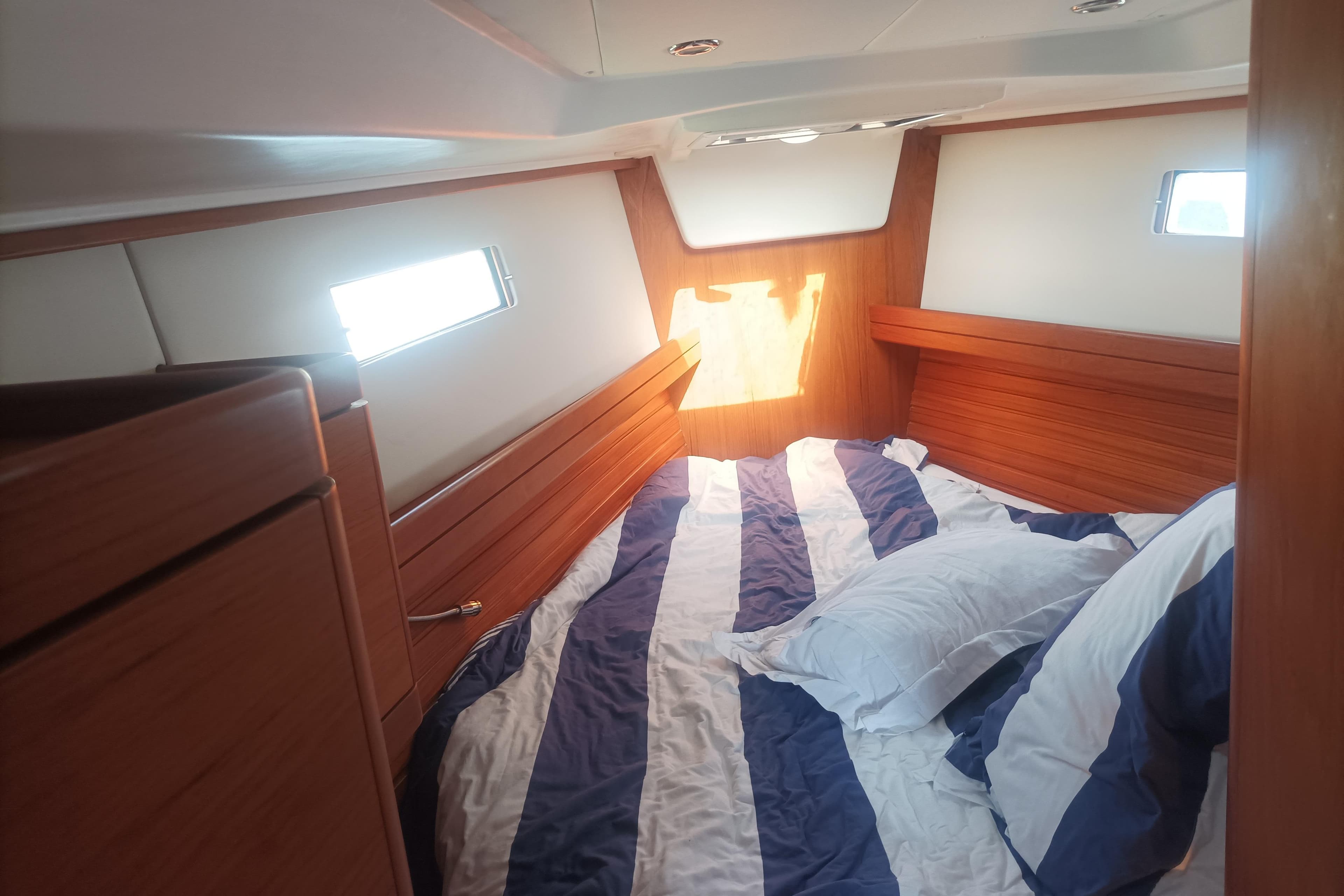 Cozy cabin interior of 2013 Wauquiez CENTURION 40S.2 with striped bedding and wooden accents.