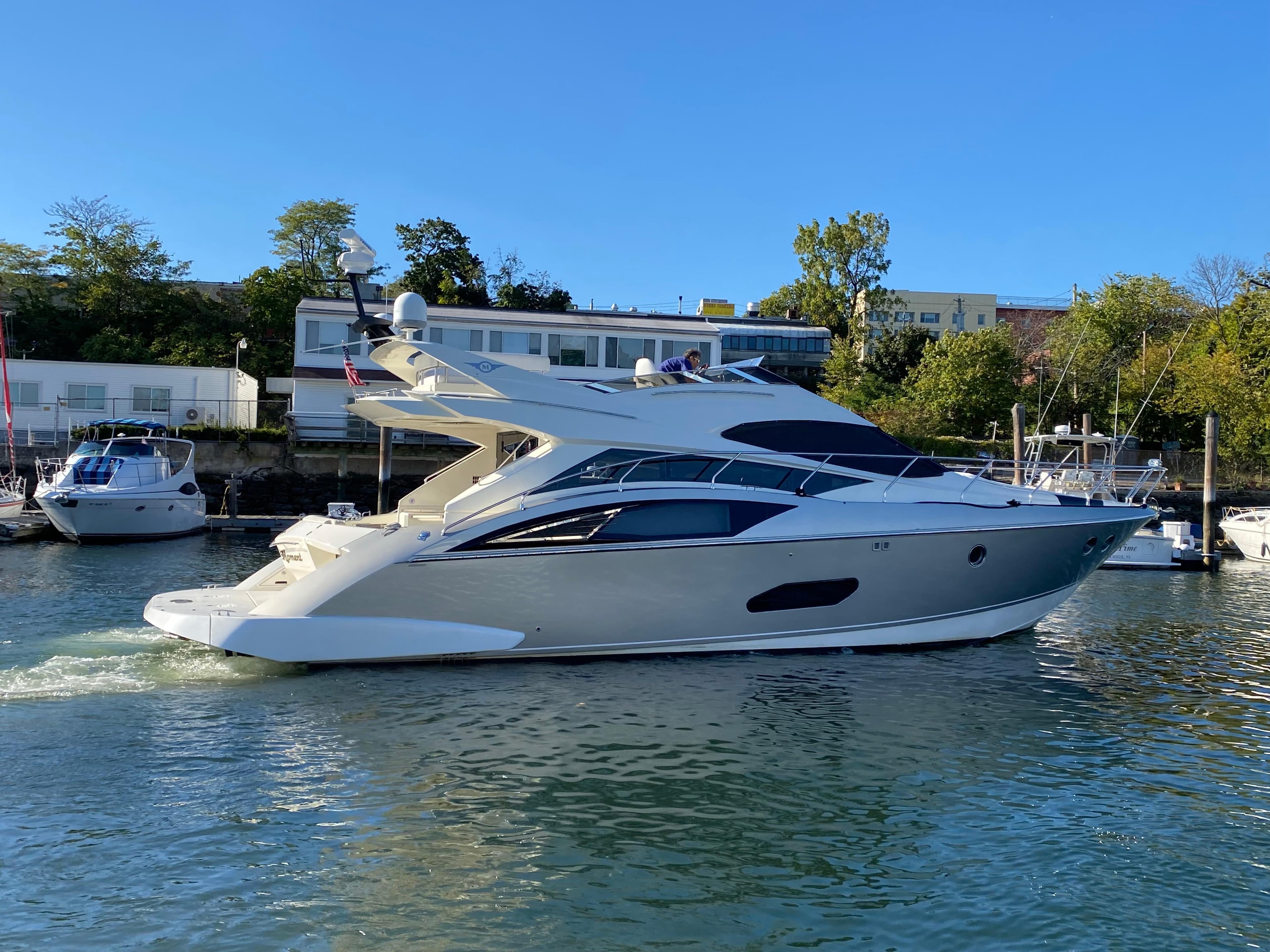 2010 Marquis 500 Sport Bridge yacht cruising in a marina under clear blue skies.