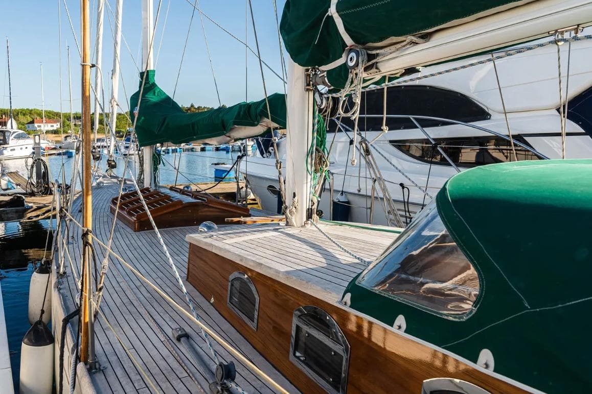 Sailboat docked in marina, RJ 140 model, 1979, with green covers and wooden deck.