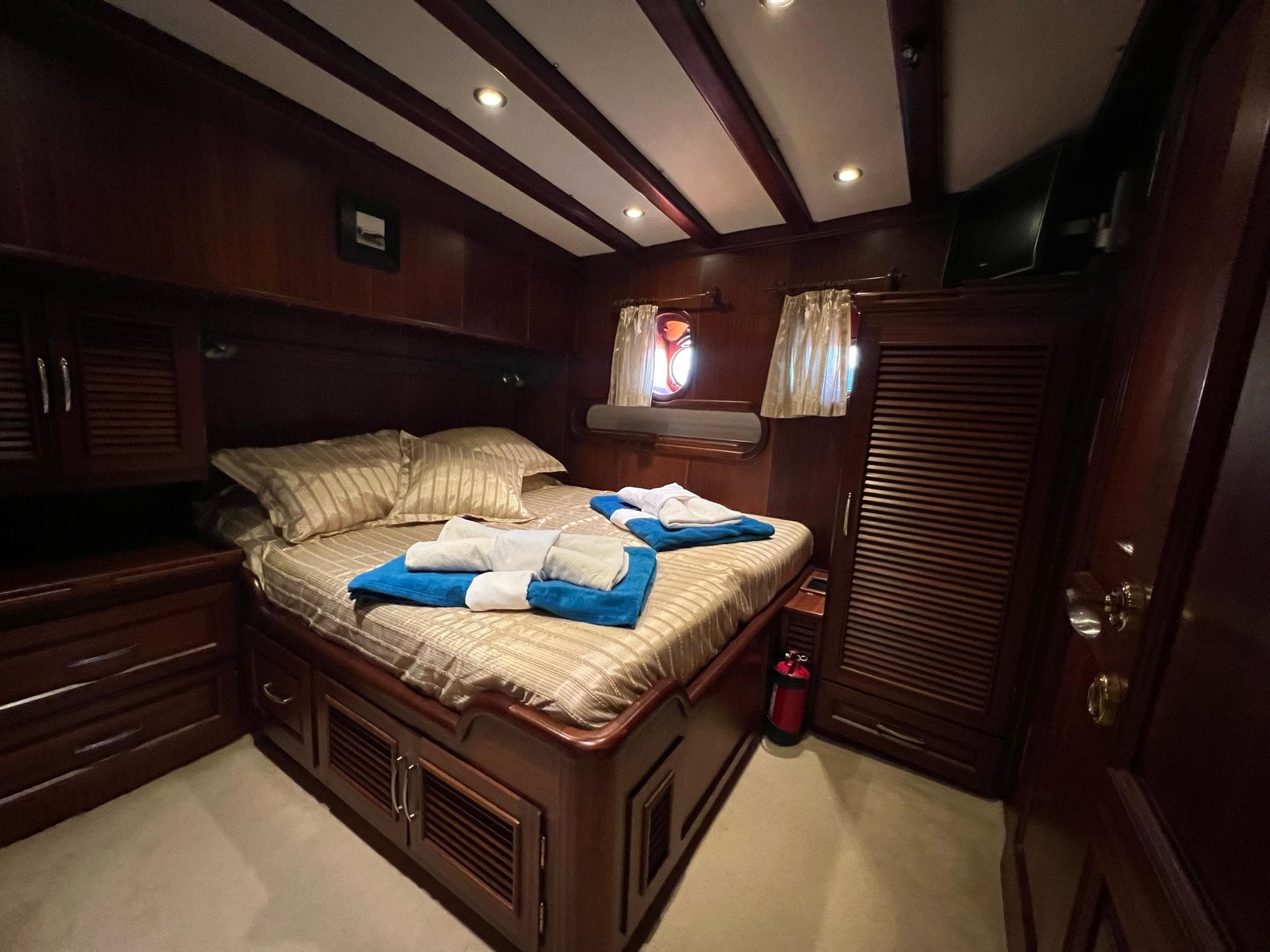 Luxurious cabin interior of 2006 Custom Gulet Ketch with cozy bed and wooden furnishings.