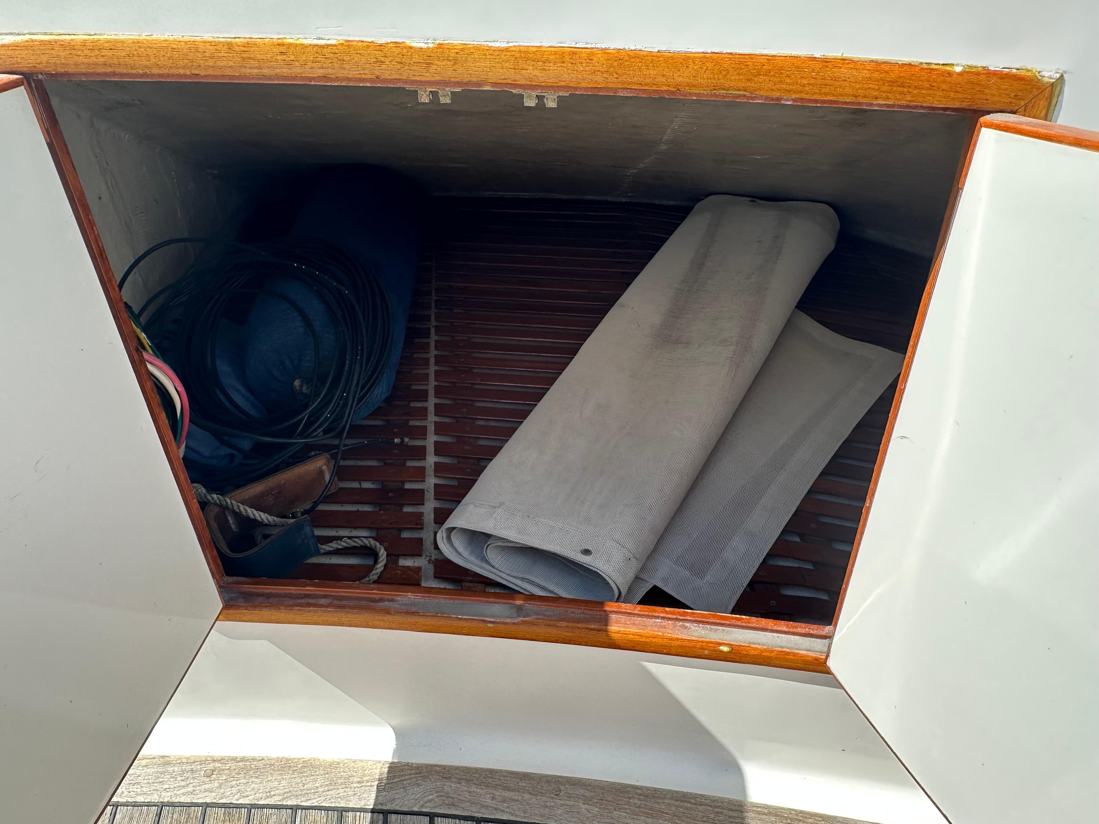 Storage compartment on 1985 Ocean Alexander Pilothouse yacht with coiled cables and rolled fabric.