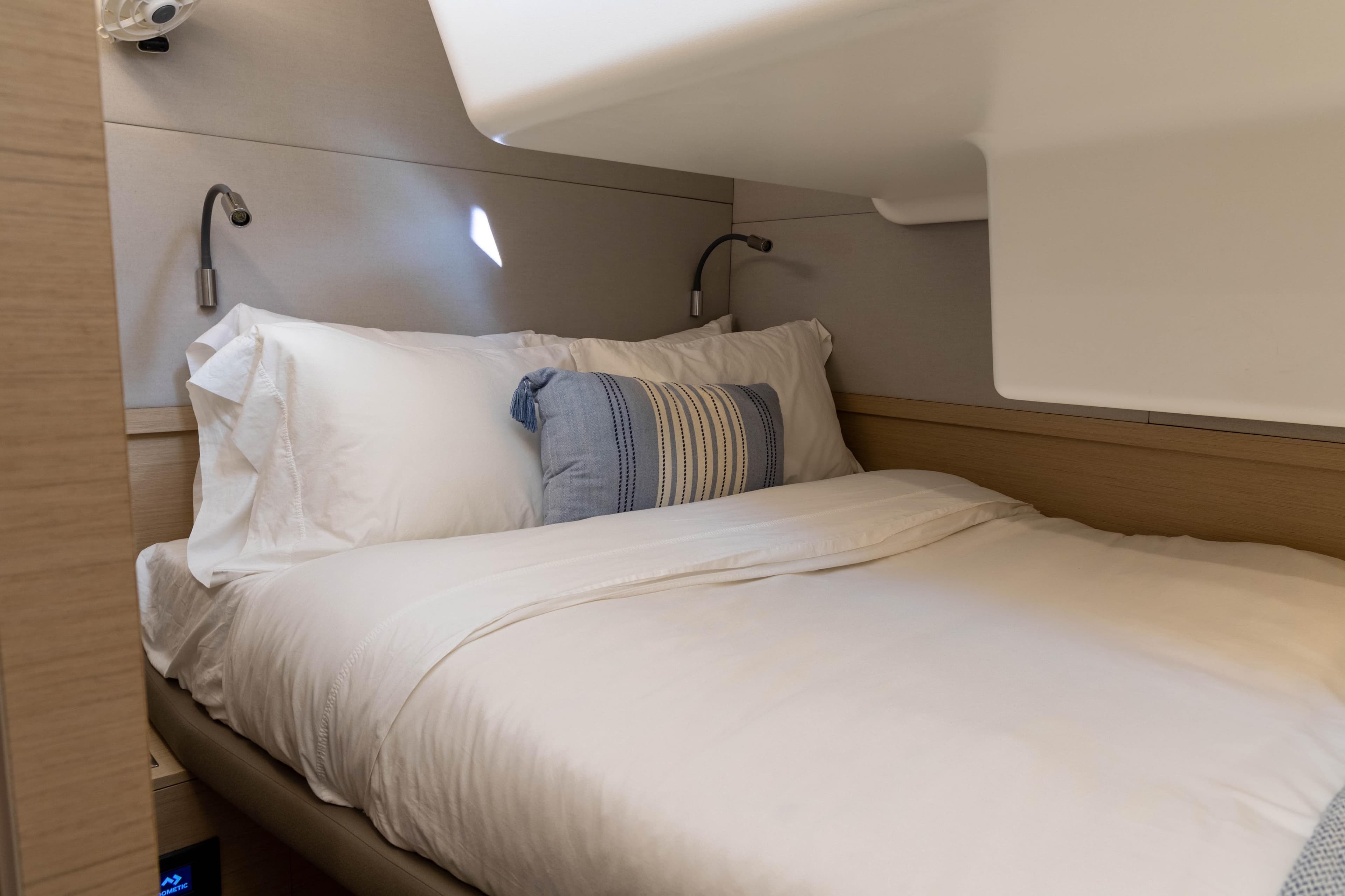 Cozy bedroom interior of 2021 Lagoon 50 yacht with elegant bedding and reading lights.