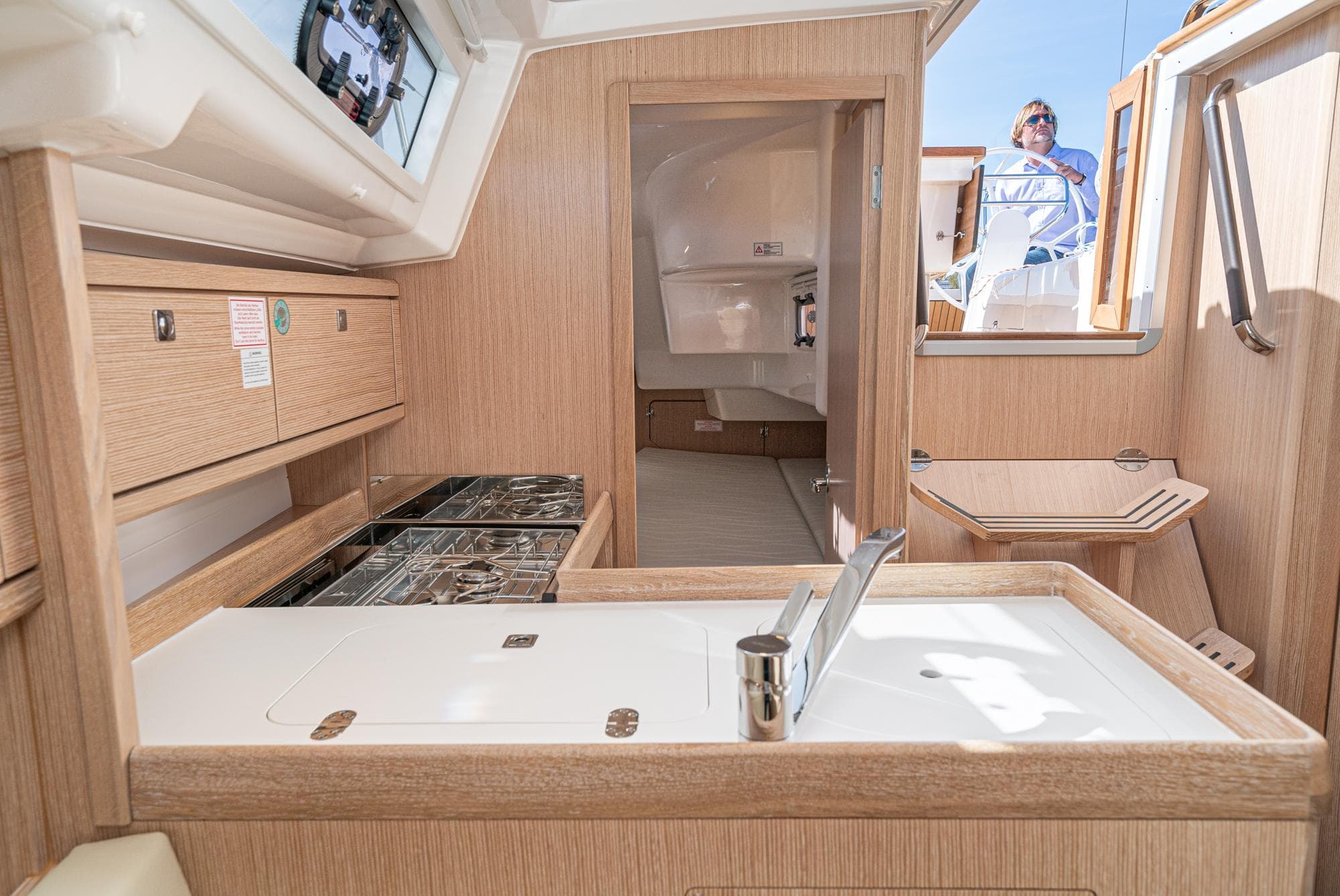 Modern interior of 2024 Bavaria Cruiser 34 yacht with wooden finishes and compact kitchen.