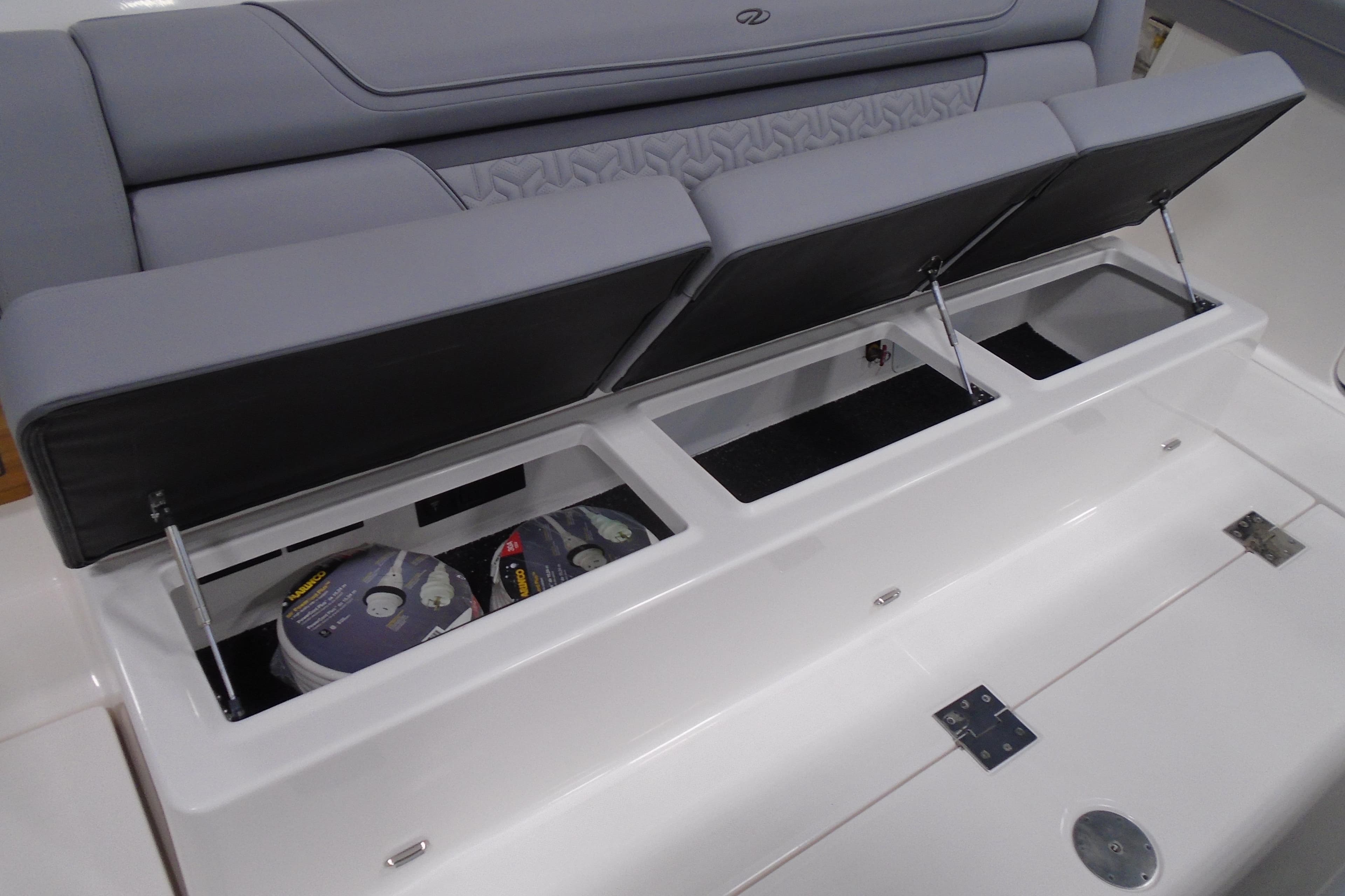2026 Regal 38 SAV boat with open storage compartments under cushioned seating.