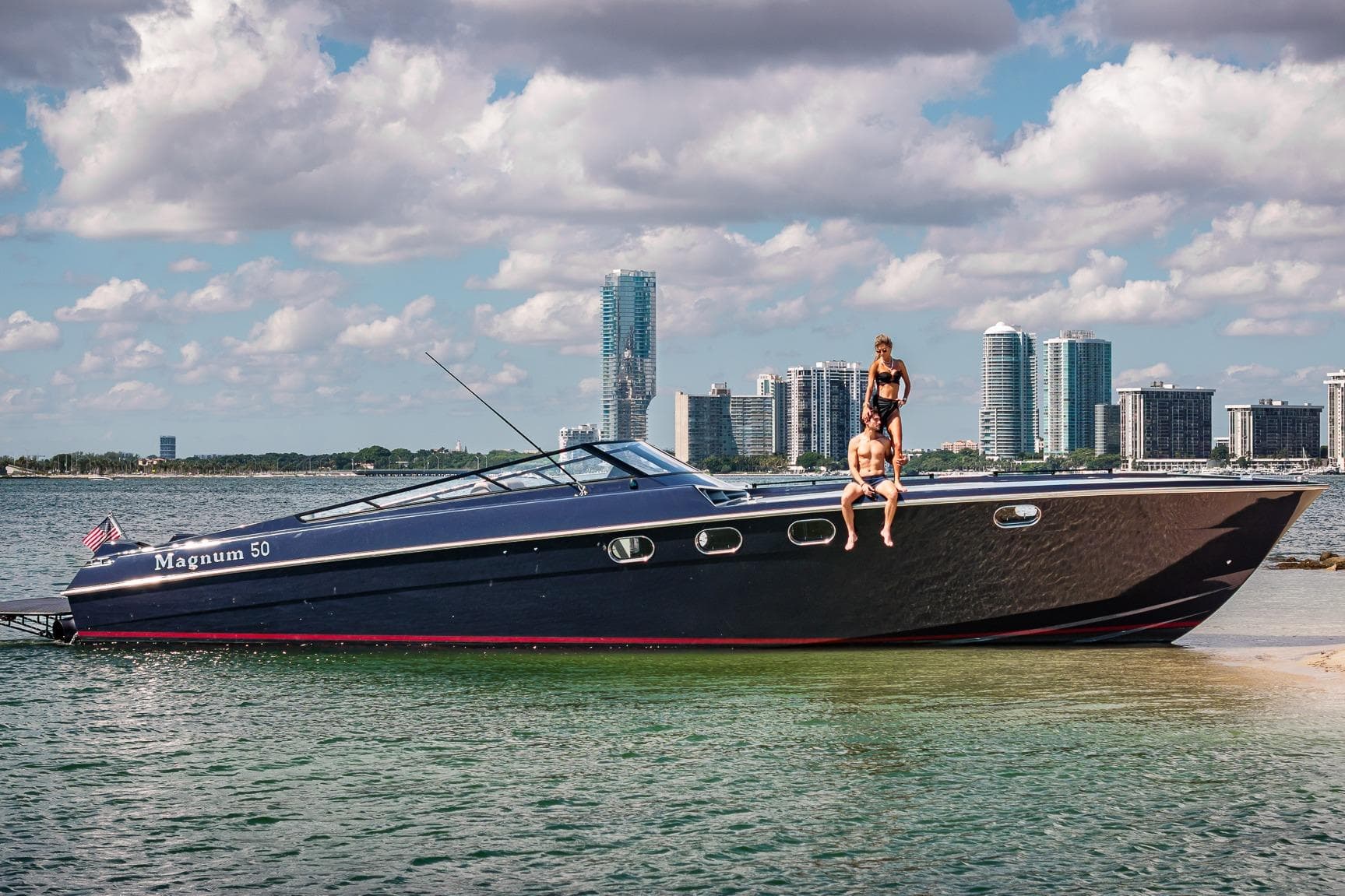 Luxury Magnum 50 Bestia yacht, 2000 model, with people onboard, city skyline in background.