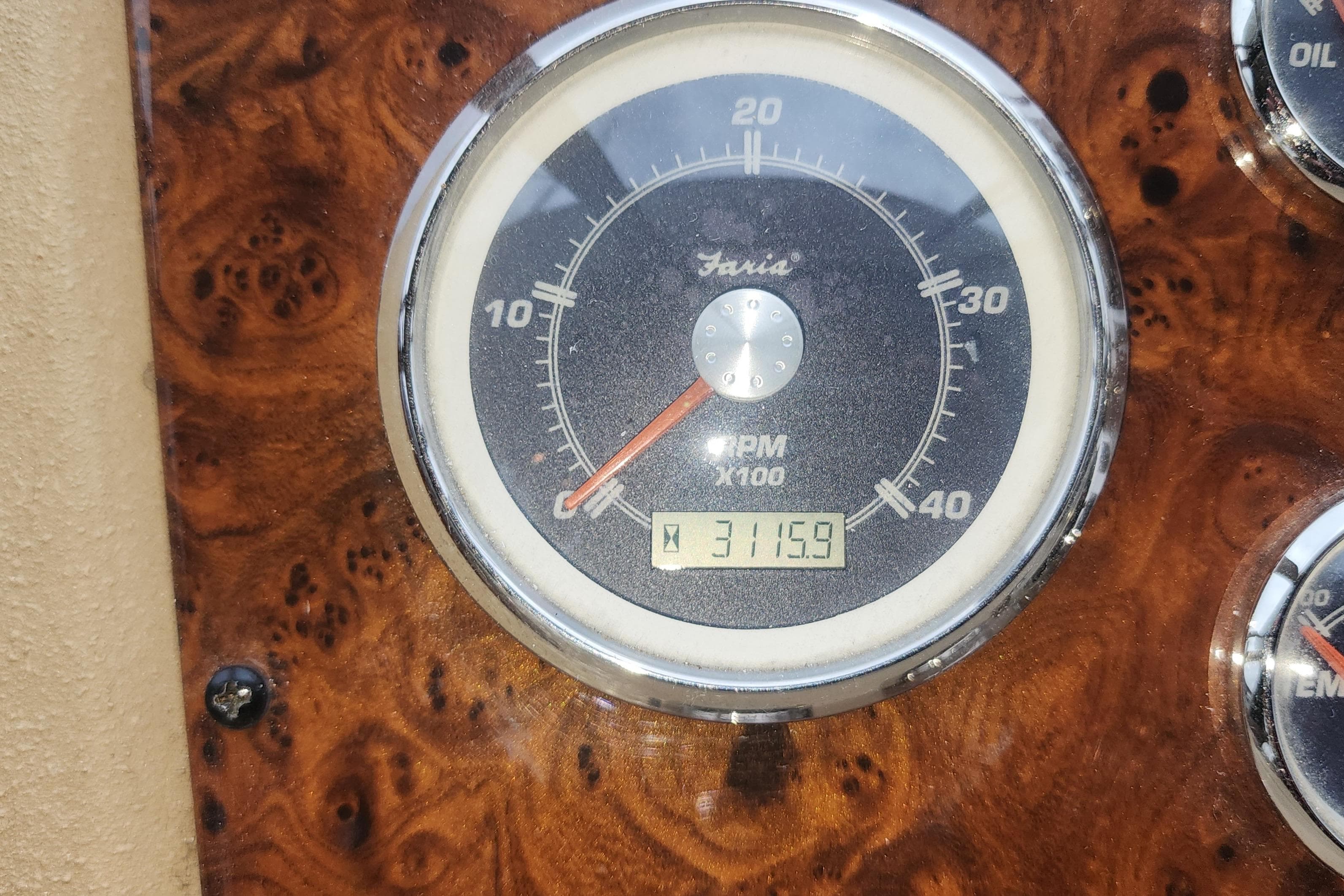 Tachometer of 2003 Meridian 490 Pilothouse showing 3115.9 RPM on wood grain dashboard.