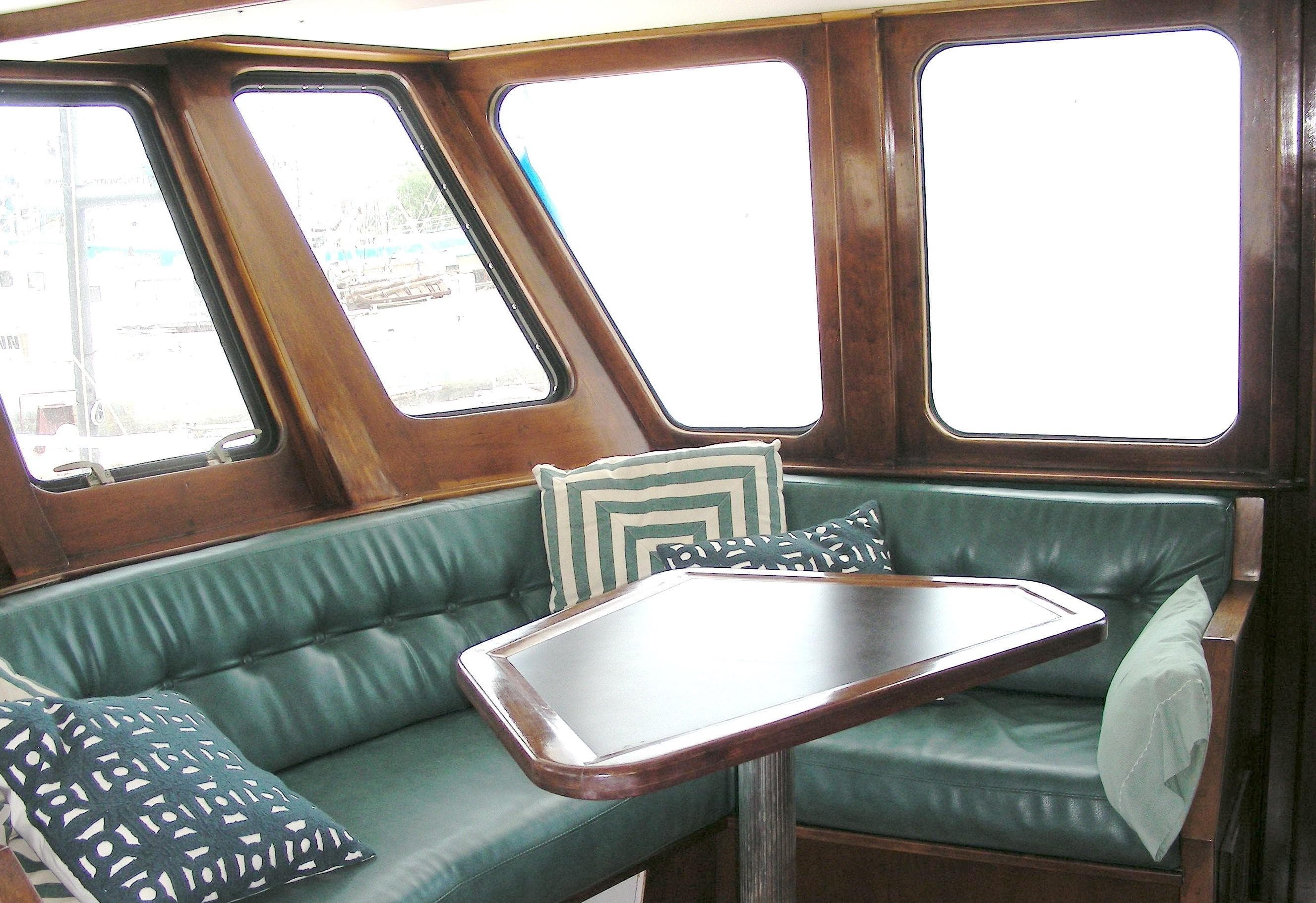 Cozy seating area in 2000 Expedition custom boat with green cushions and decorative pillows.