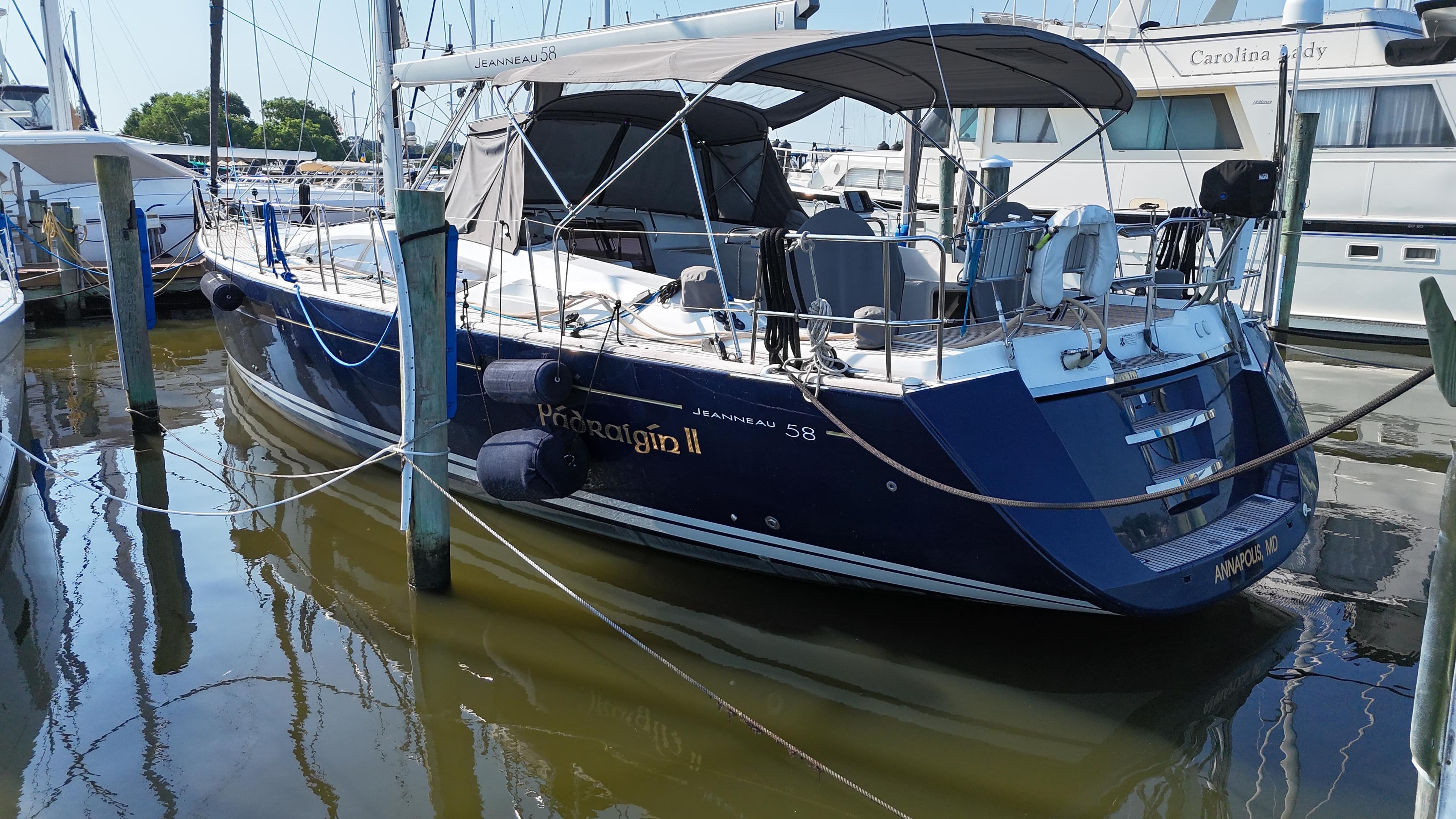 2016 Jeanneau Yachts 58 docked in marina, blue hull, covered cockpit.