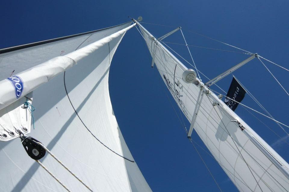 Sailing yacht Discovery 55, 2011 model, with sails unfurled against a clear blue sky.