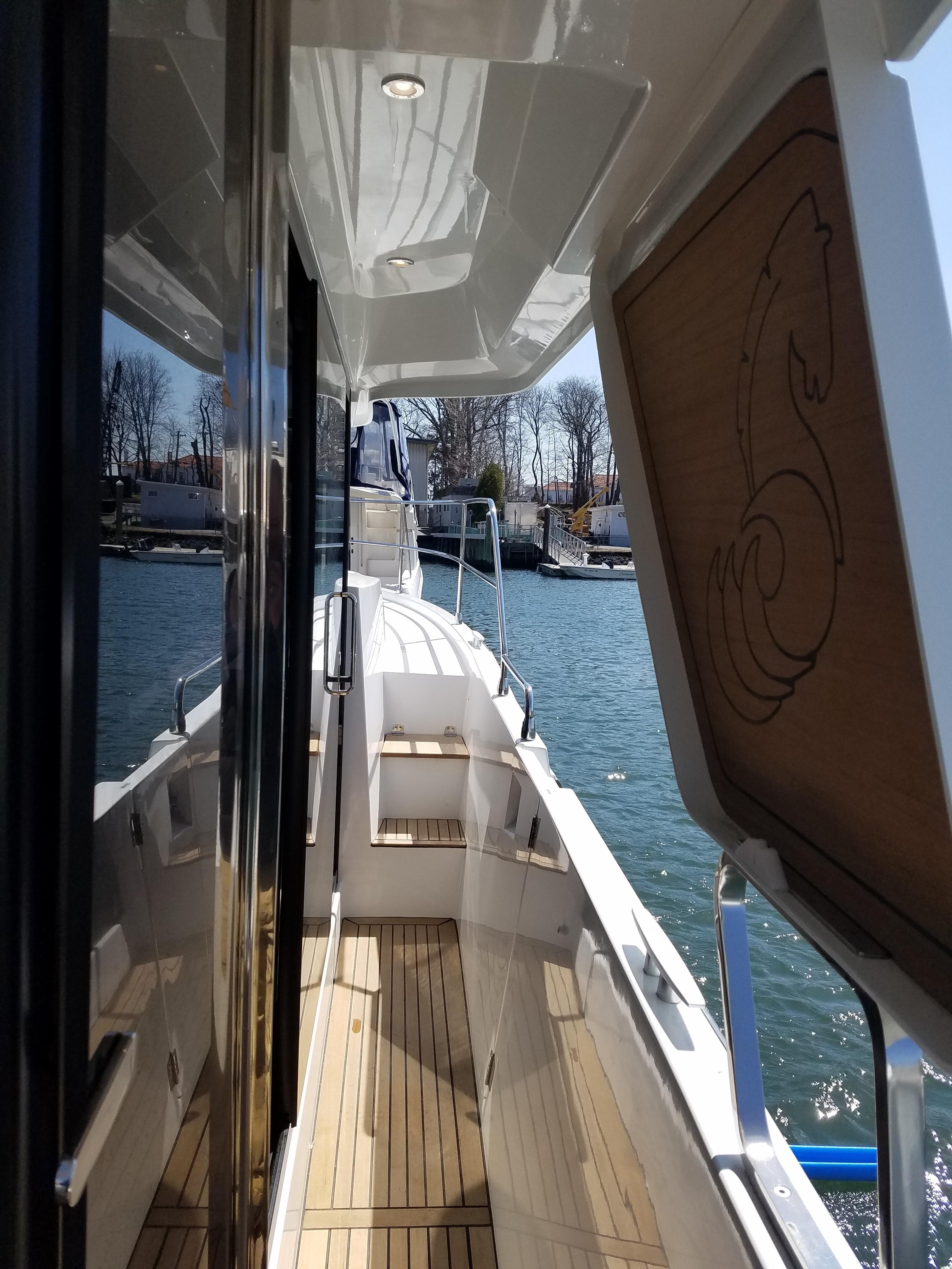 2019 Beneteau Swift Trawler 35, side deck view with wood accents and water backdrop.
