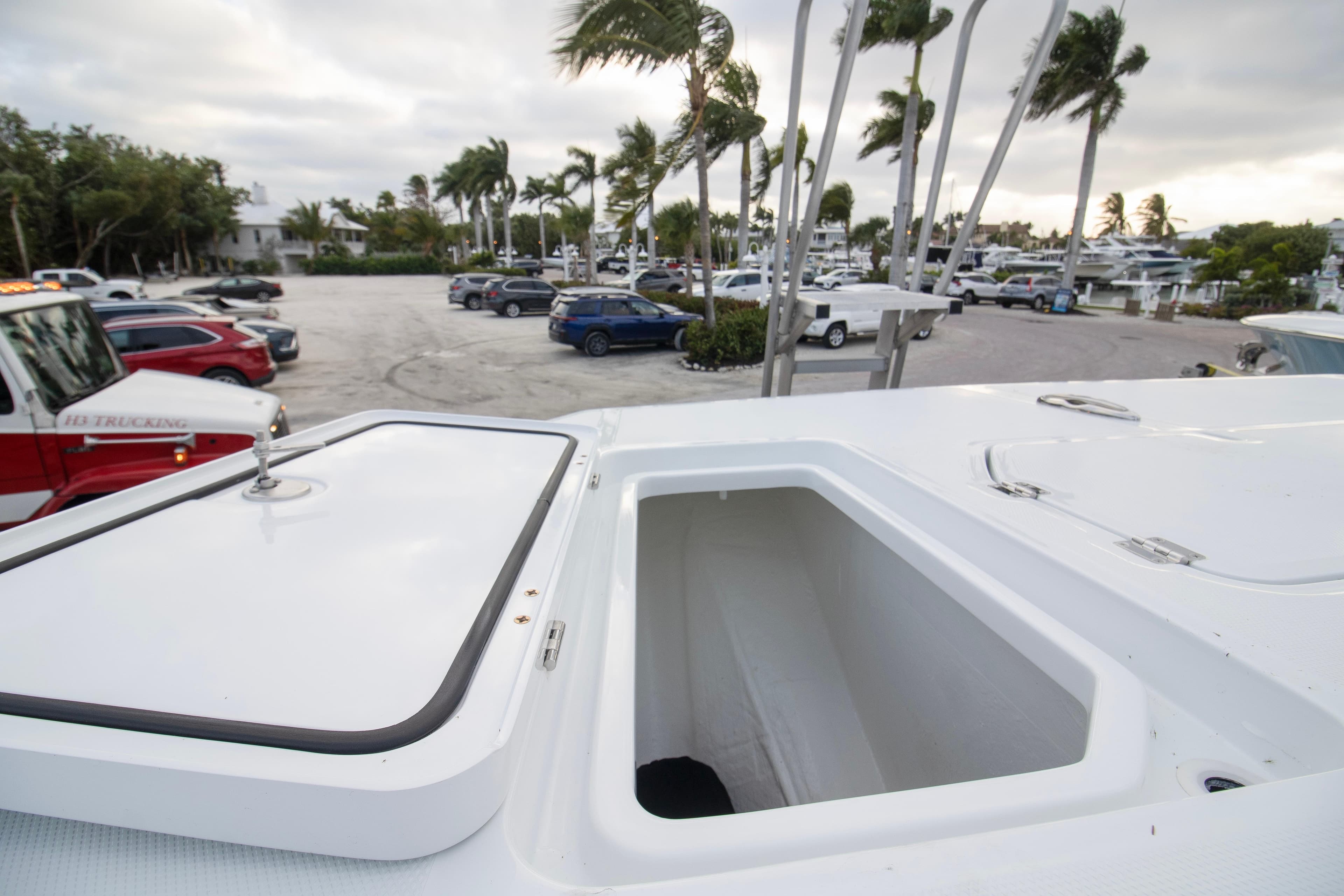2026 Invincible 38 Catamaran with open storage compartment, parked near marina with palm trees.