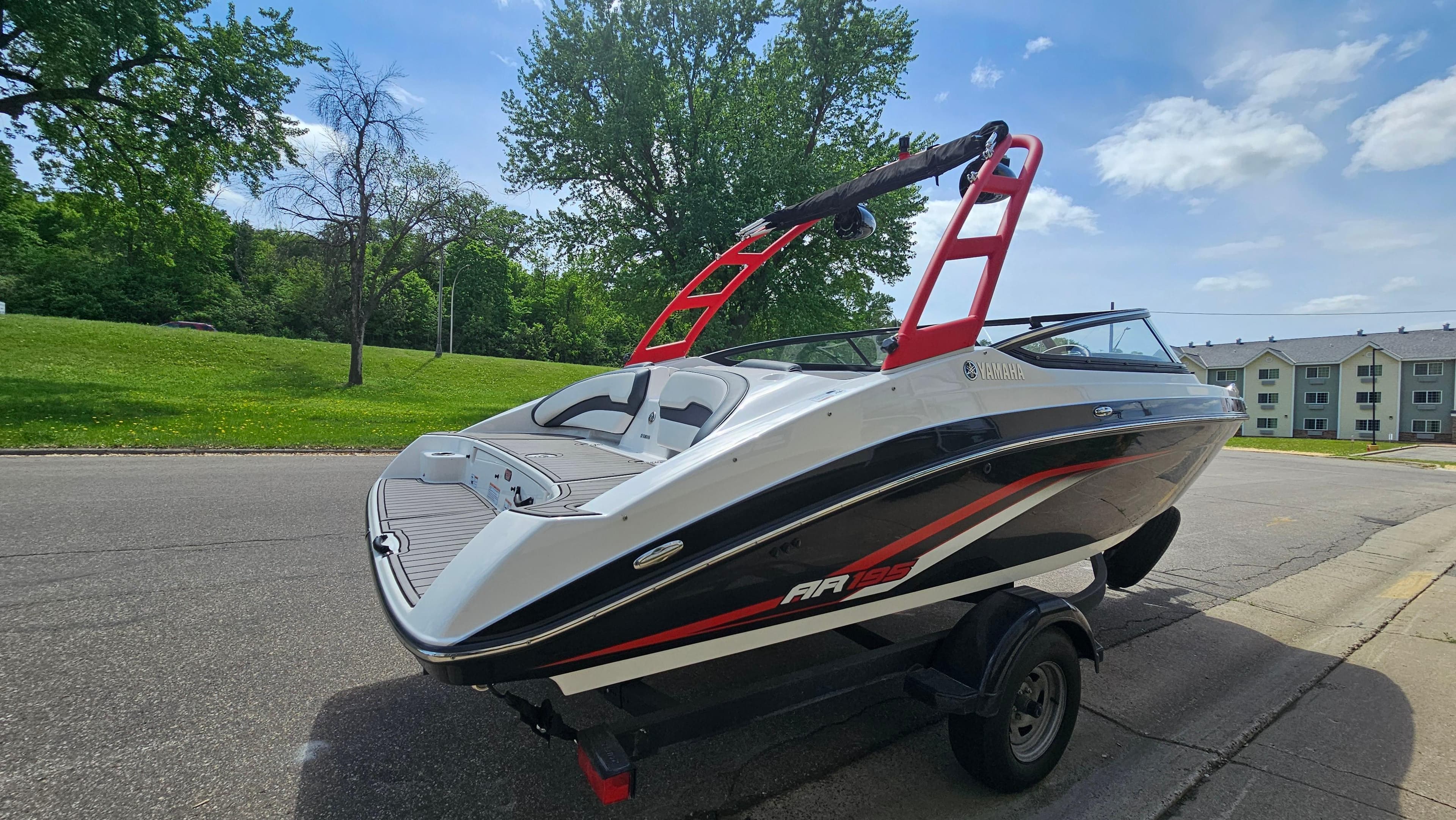 2019 Yamaha AR195 boat on trailer, parked on a sunny street with trees and buildings.