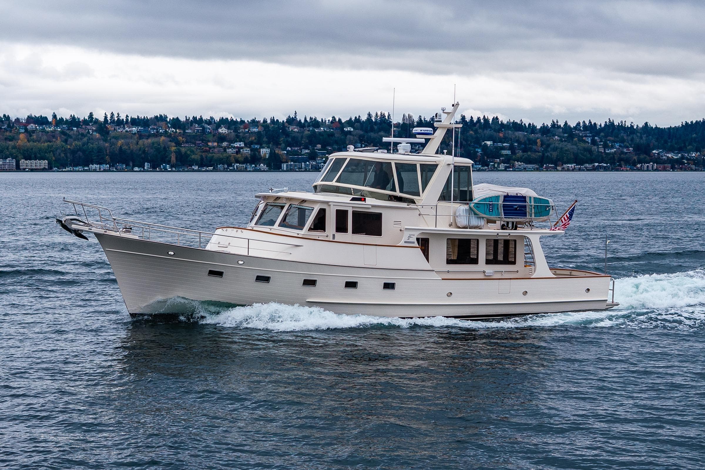 2026 Fleming 55 Pilothouse yacht cruising on a scenic lake under cloudy skies.