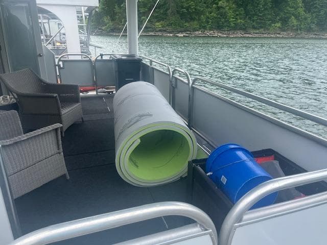 2009 Horizon 18 x 85 Houseboat deck with rolled carpet and blue bucket.
