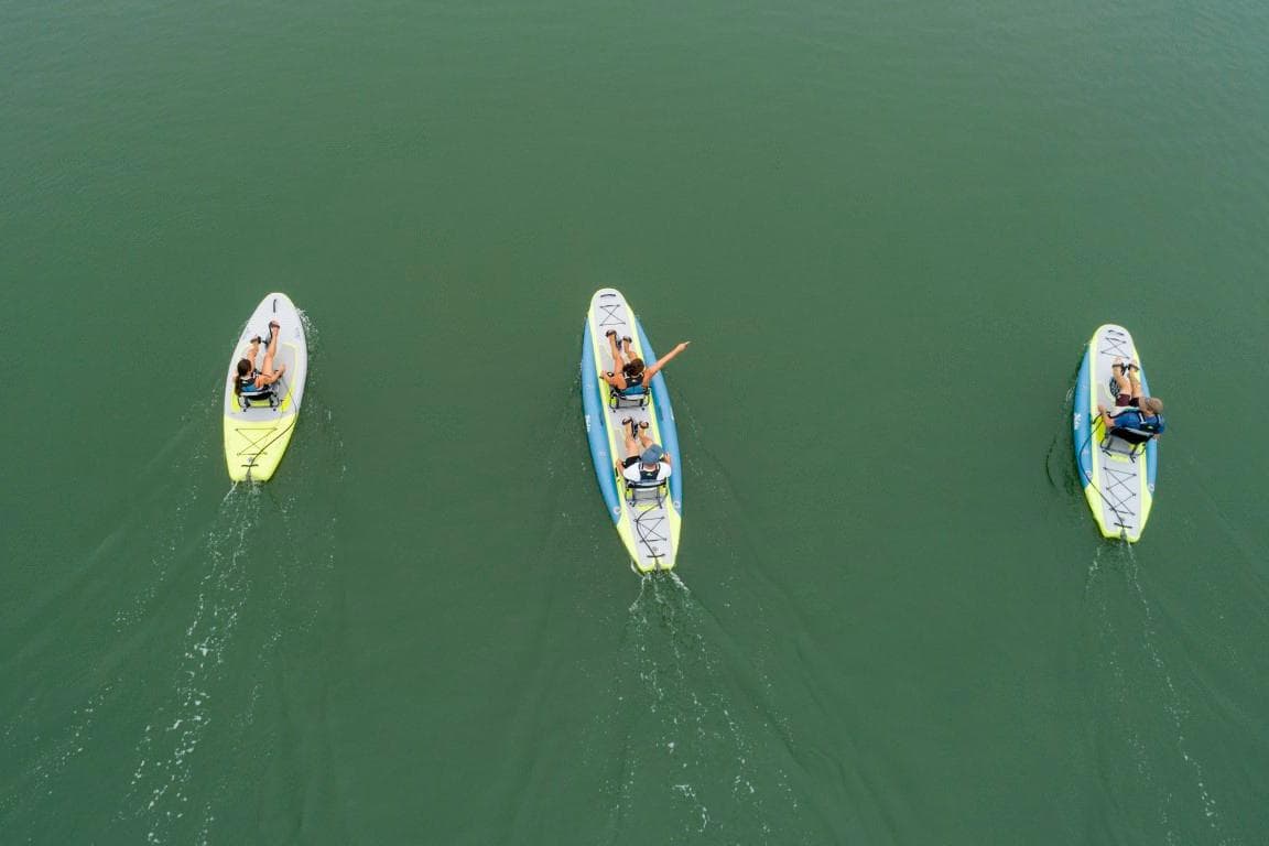 Three Hobie iTrek 14 Duo kayaks on calm water, 2025 model.
