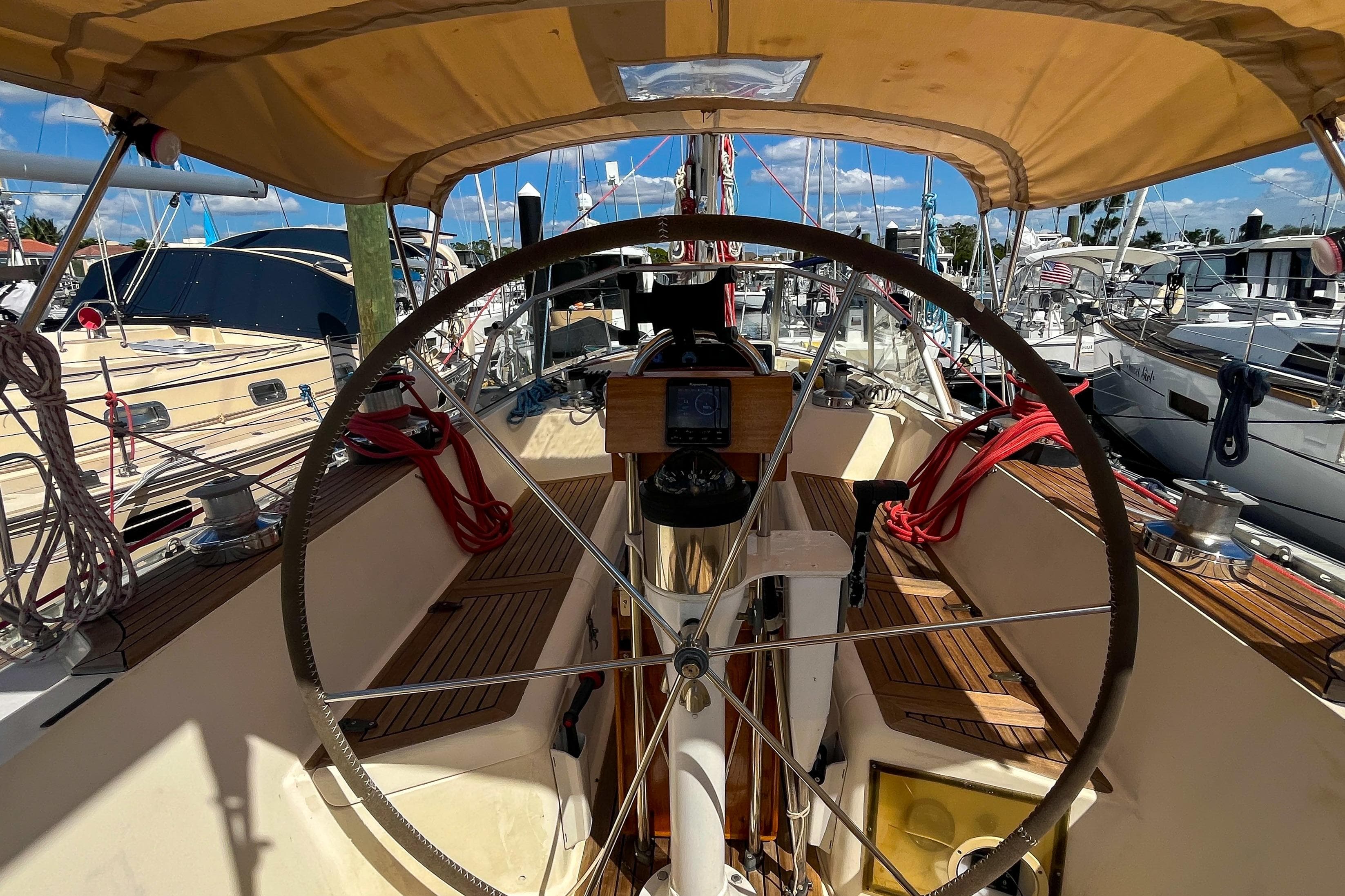 Cockpit of 1991 Oyster LW48 sailboat with wooden deck and steering wheel.