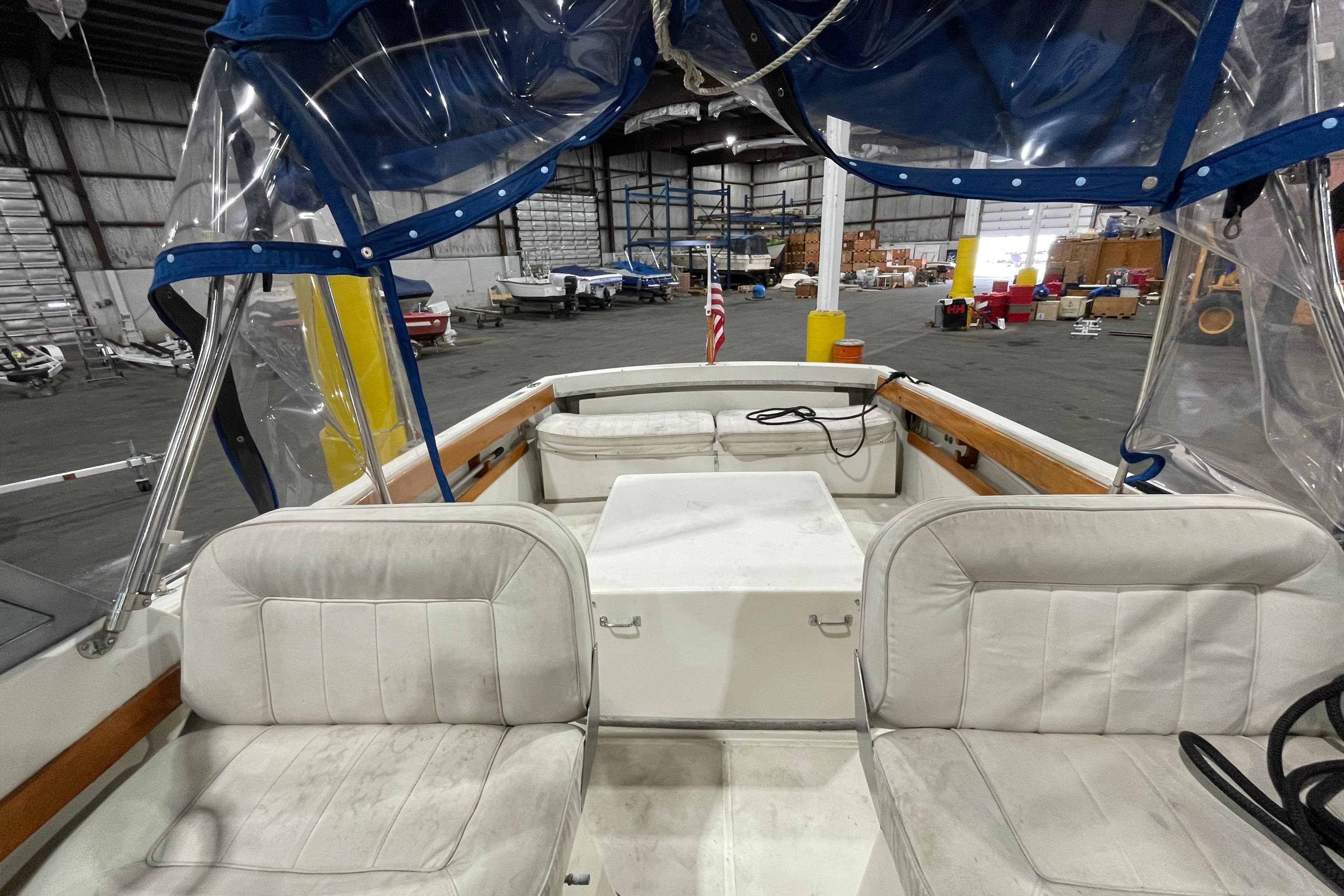 1989 Limestone 24 boat interior with white seating and blue canopy in a warehouse.