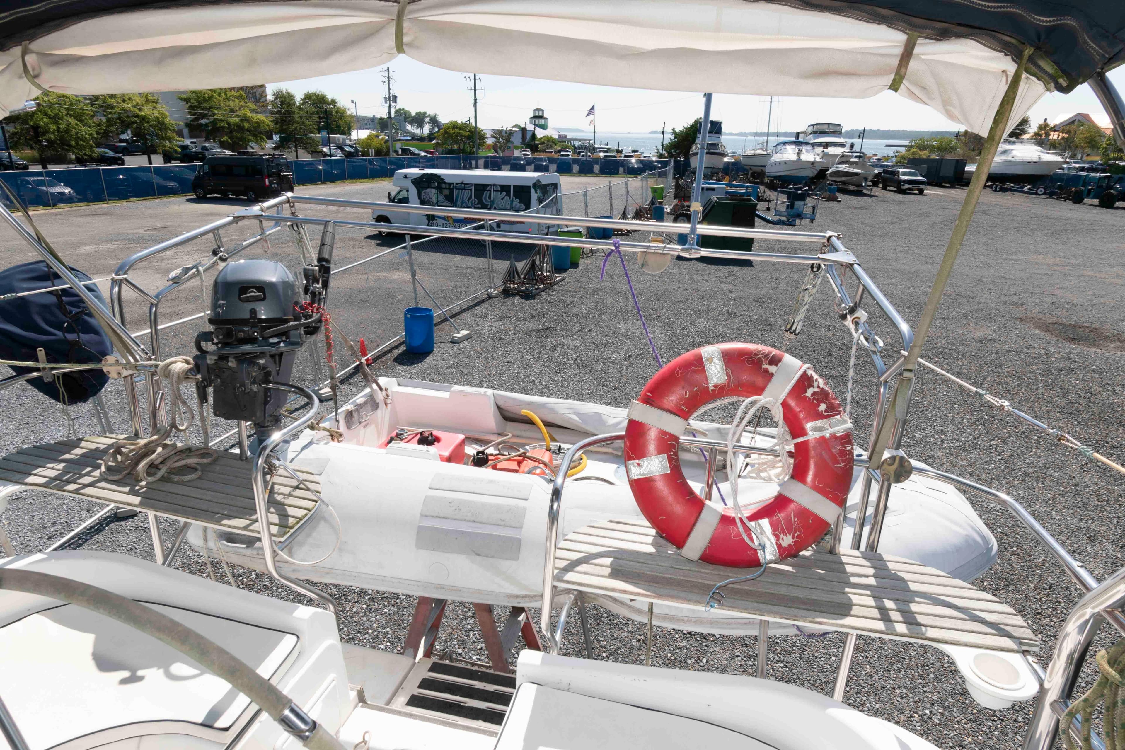 Hunter 44 Deck Salon 2006 sailboat stern with lifebuoy and outboard motor in marina.
