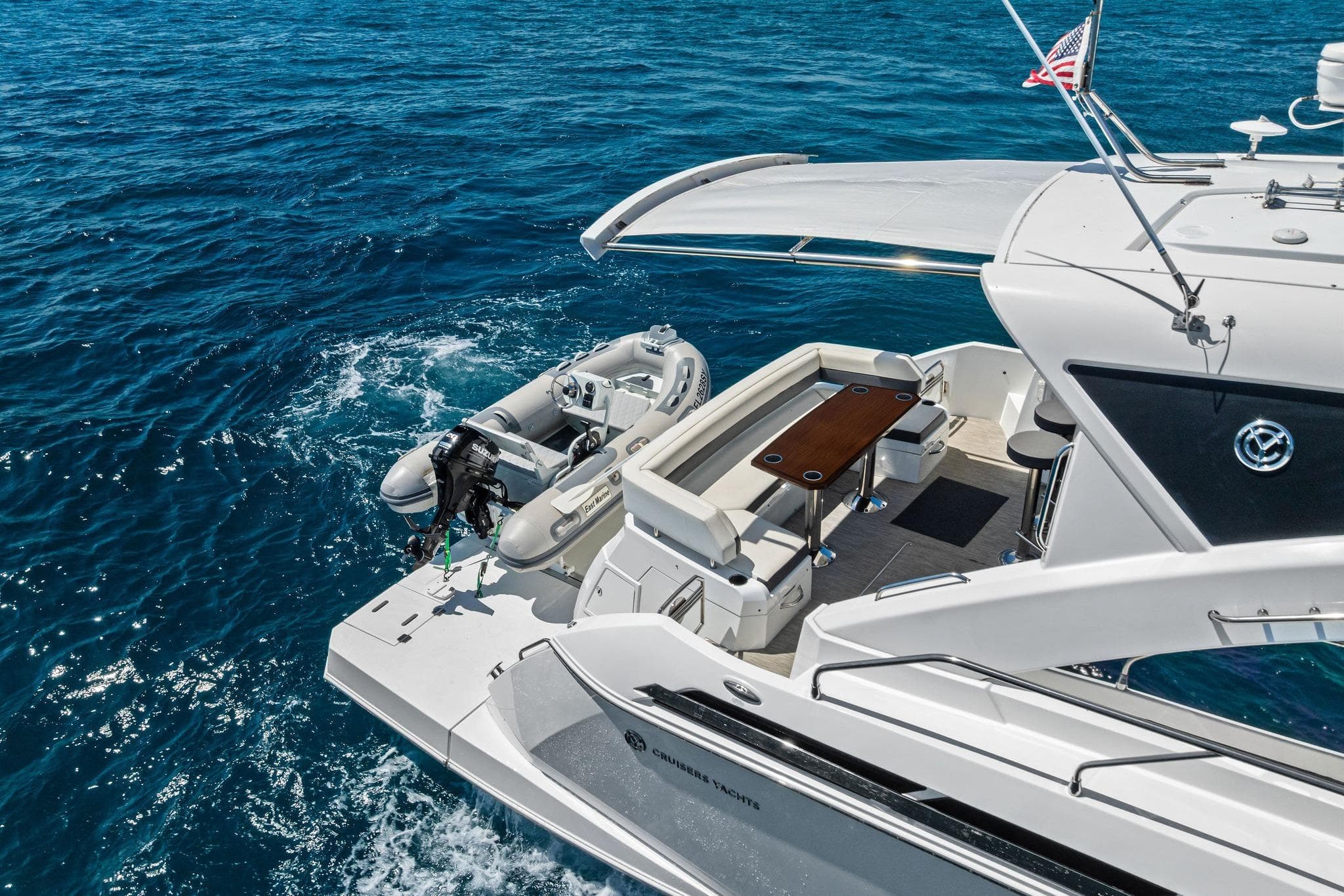 2019 Cruisers Yachts 54 Cantius on open sea, featuring spacious deck and tender boat.