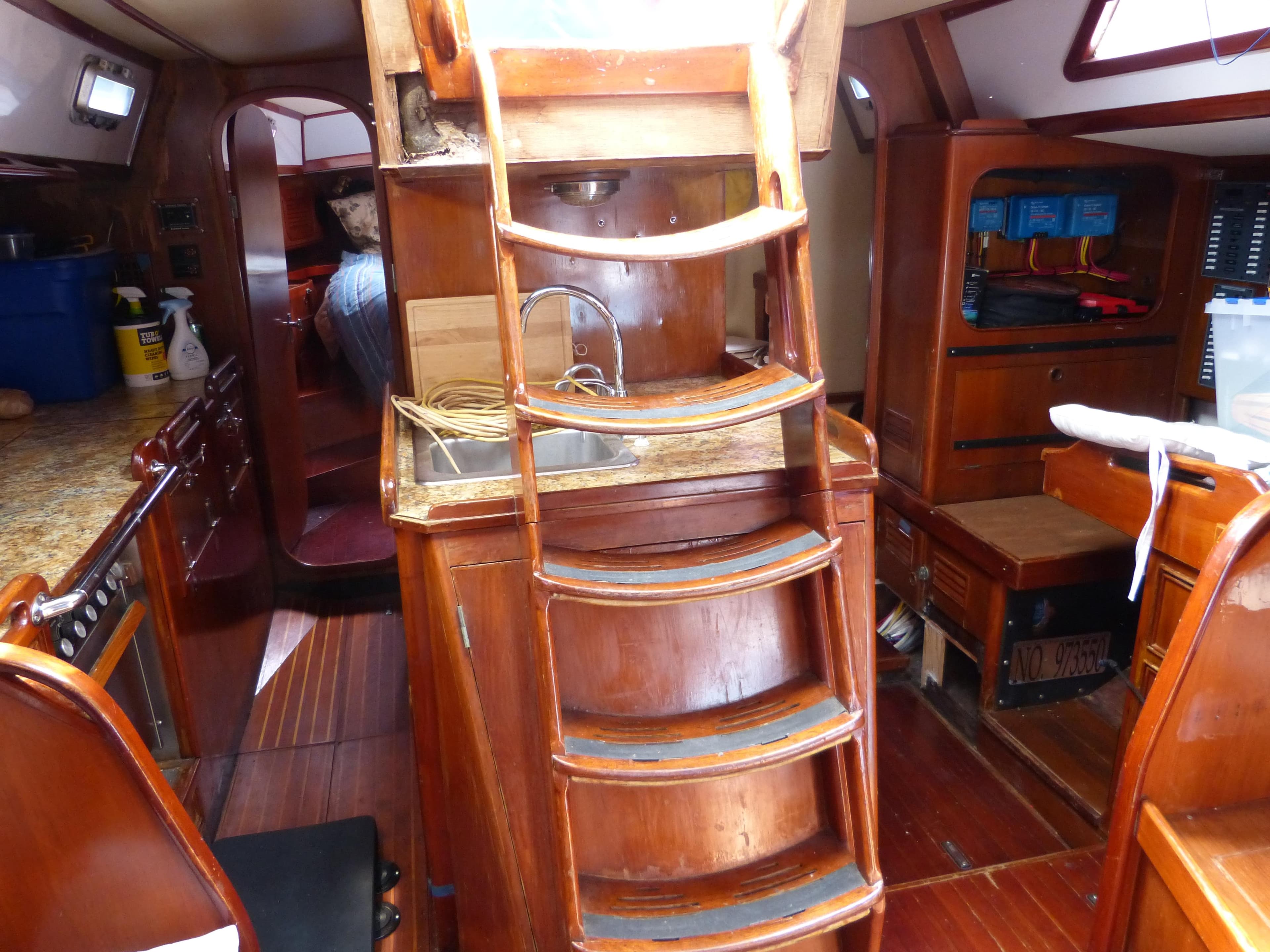 Interior of a 1990 Hylas 44 sailboat with wooden cabinetry and compact kitchen area.