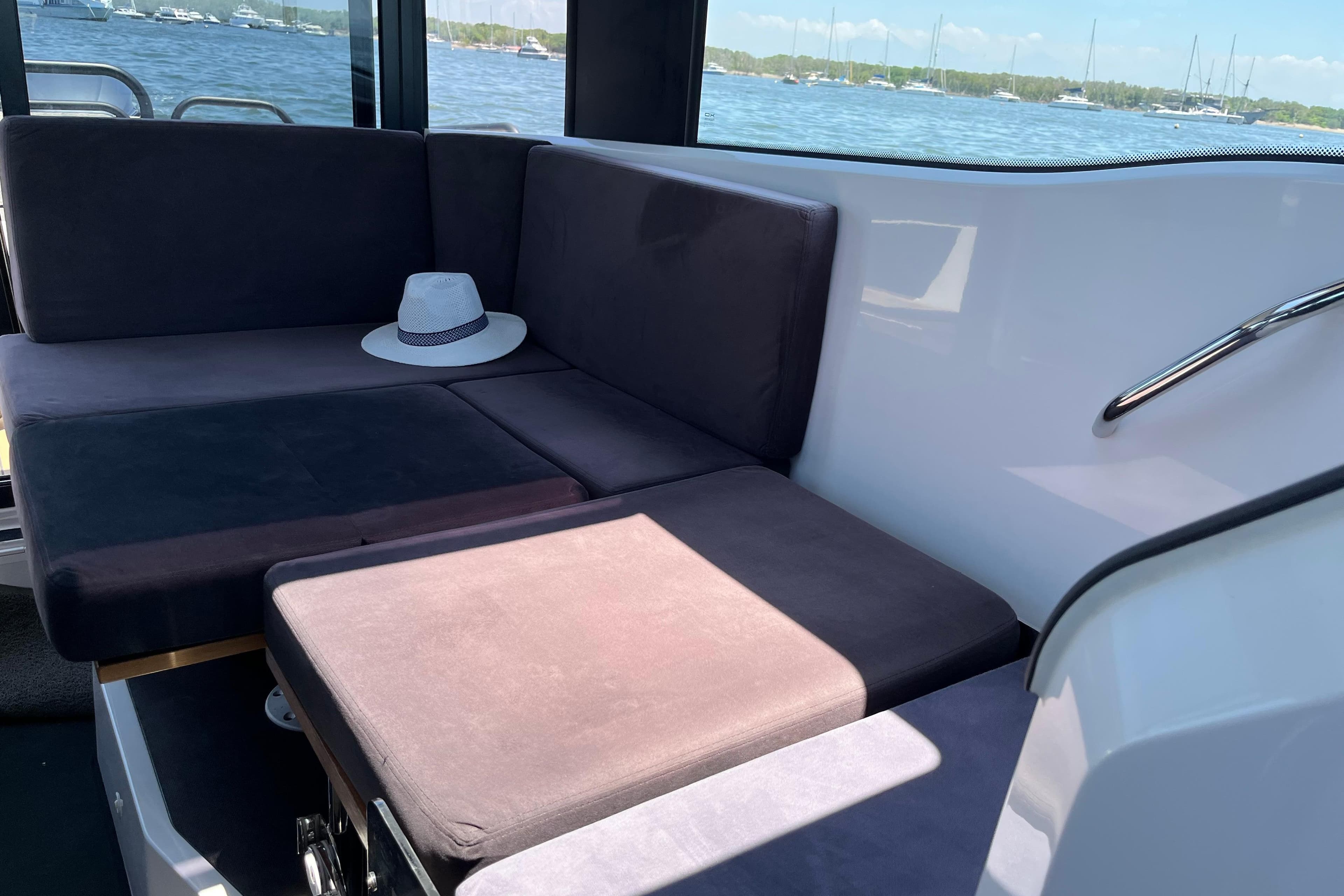 Interior of 2021 XO Boats 270 Explorer with seating and a hat, overlooking water.