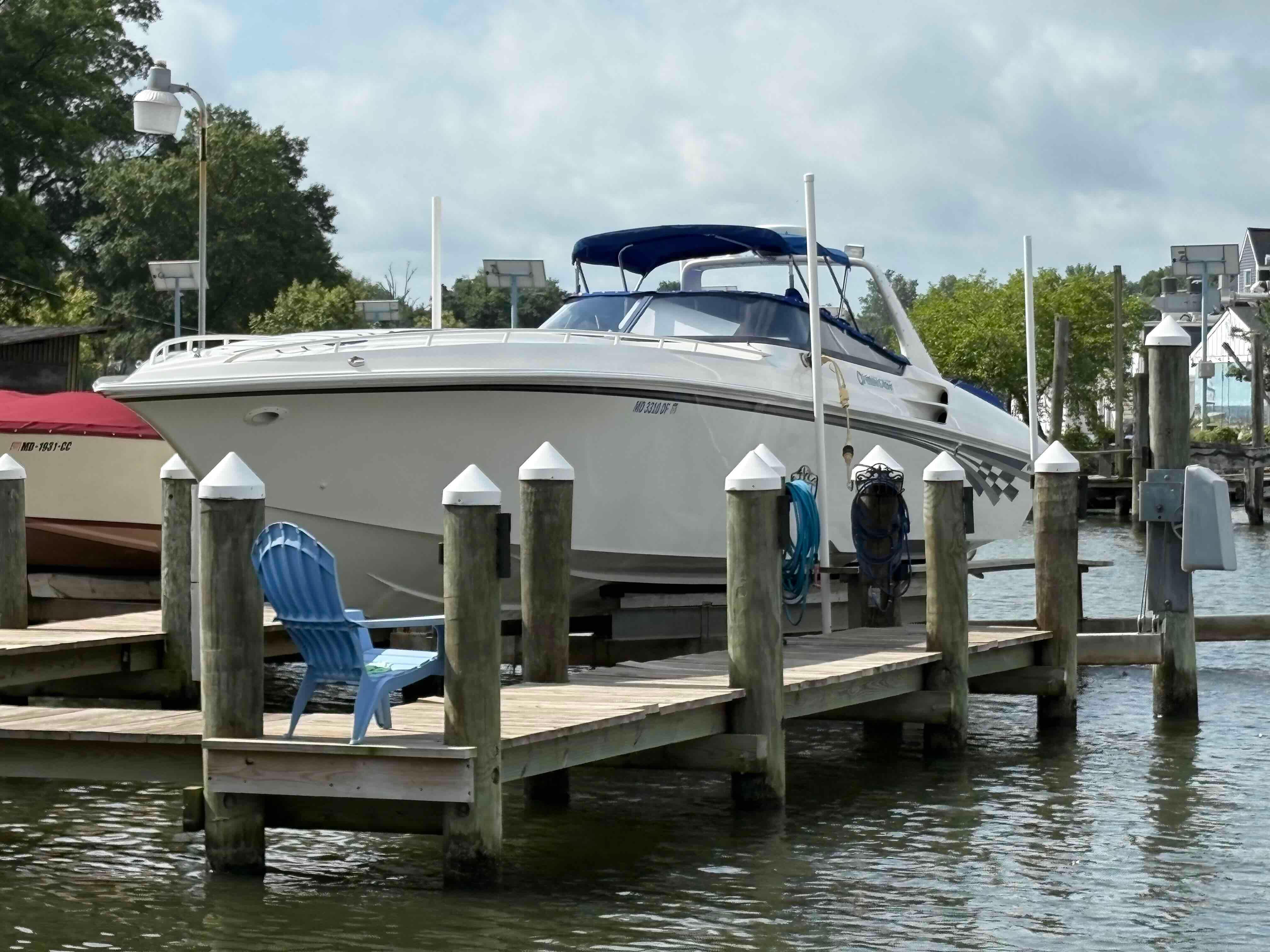 1999 Fountain 47 Lightning boat docked at marina with blue chair nearby.