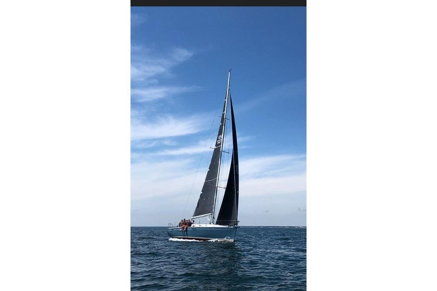 Sailing yacht Beneteau First 44.7 (2005) gliding on open sea under clear blue sky.