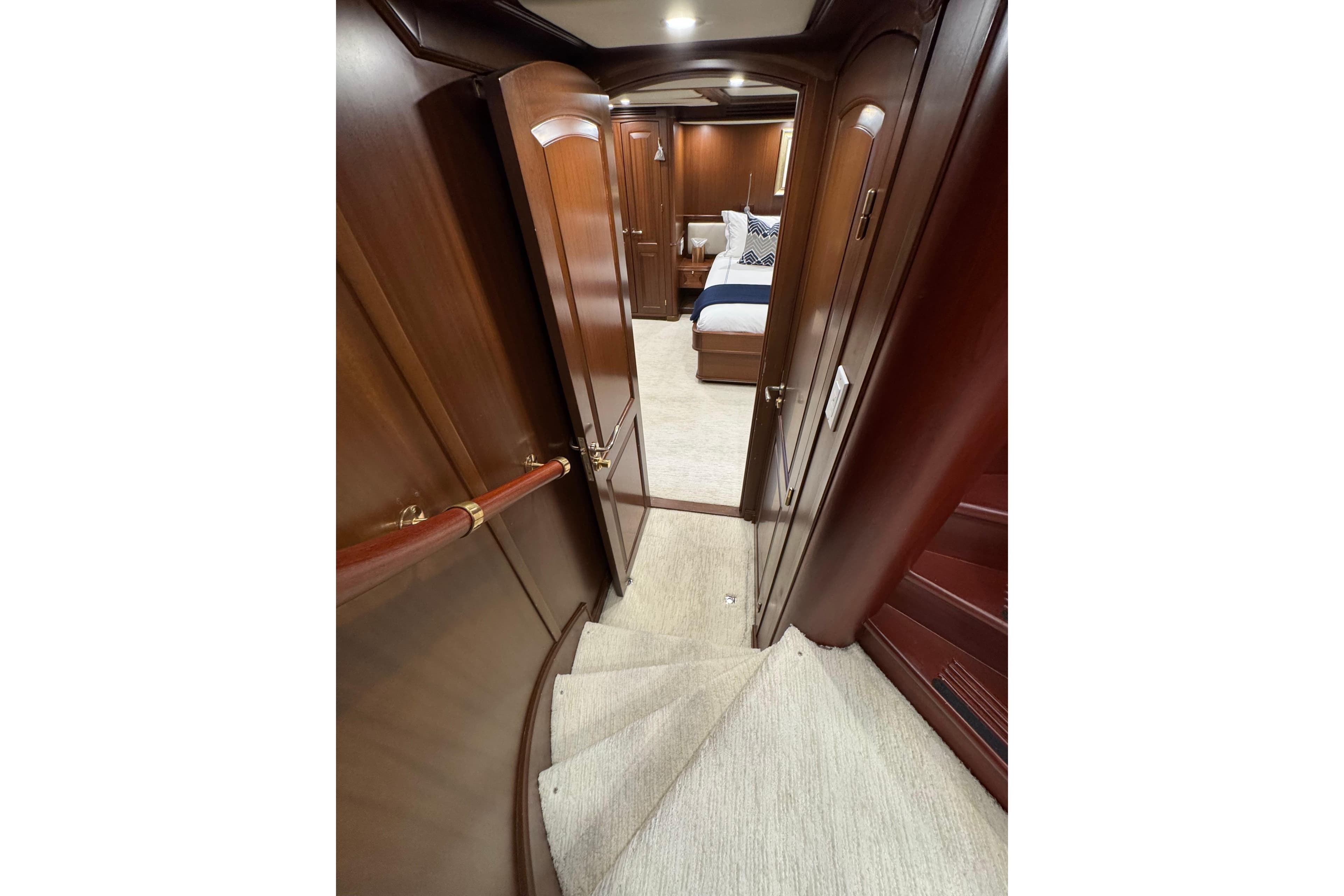 Luxurious wooden interior of 2001 Doogersbank Vipack yacht, featuring elegant staircase and cozy bedroom.