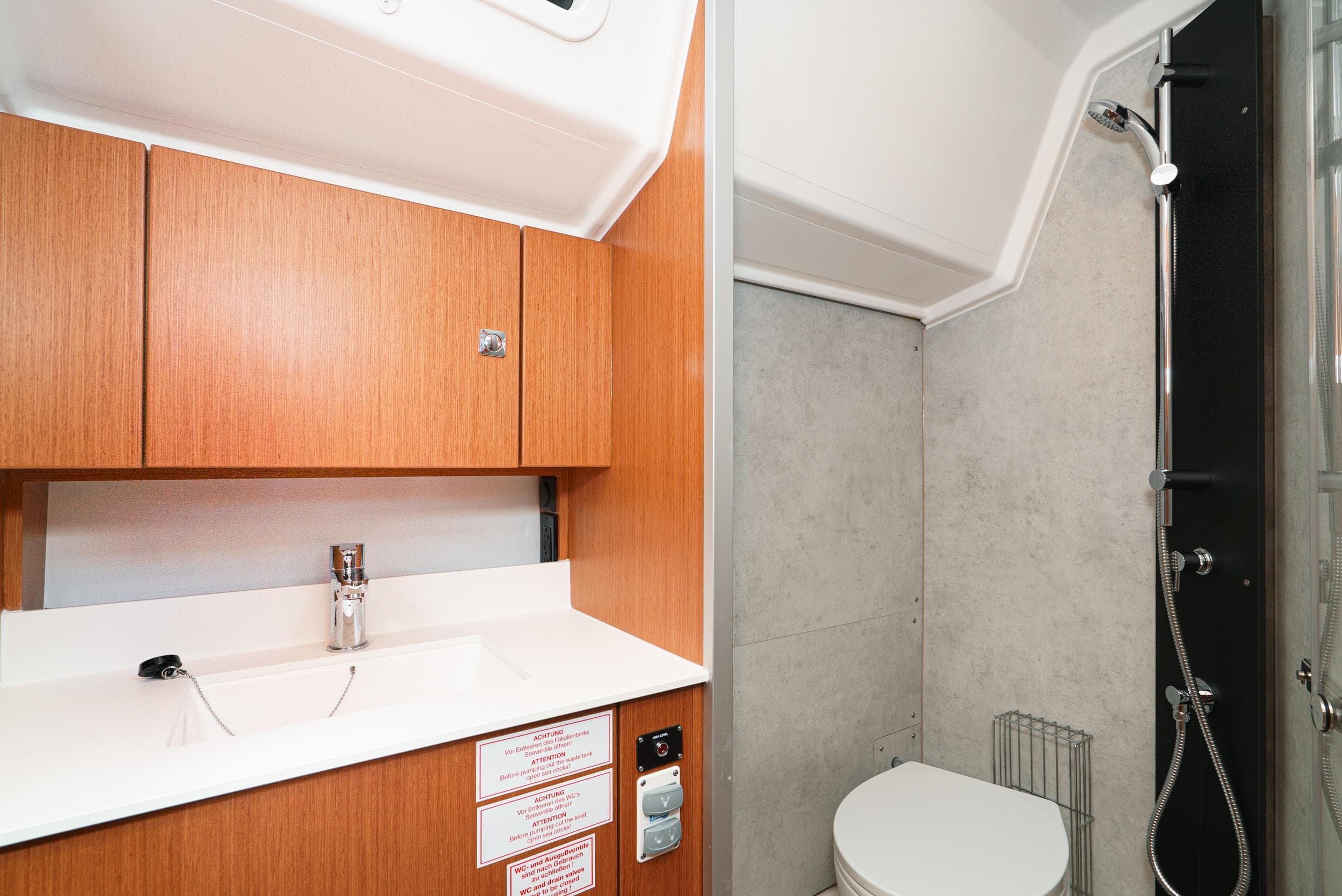 2024 Bavaria C42 yacht bathroom with wooden cabinets, sink, toilet, and shower.
