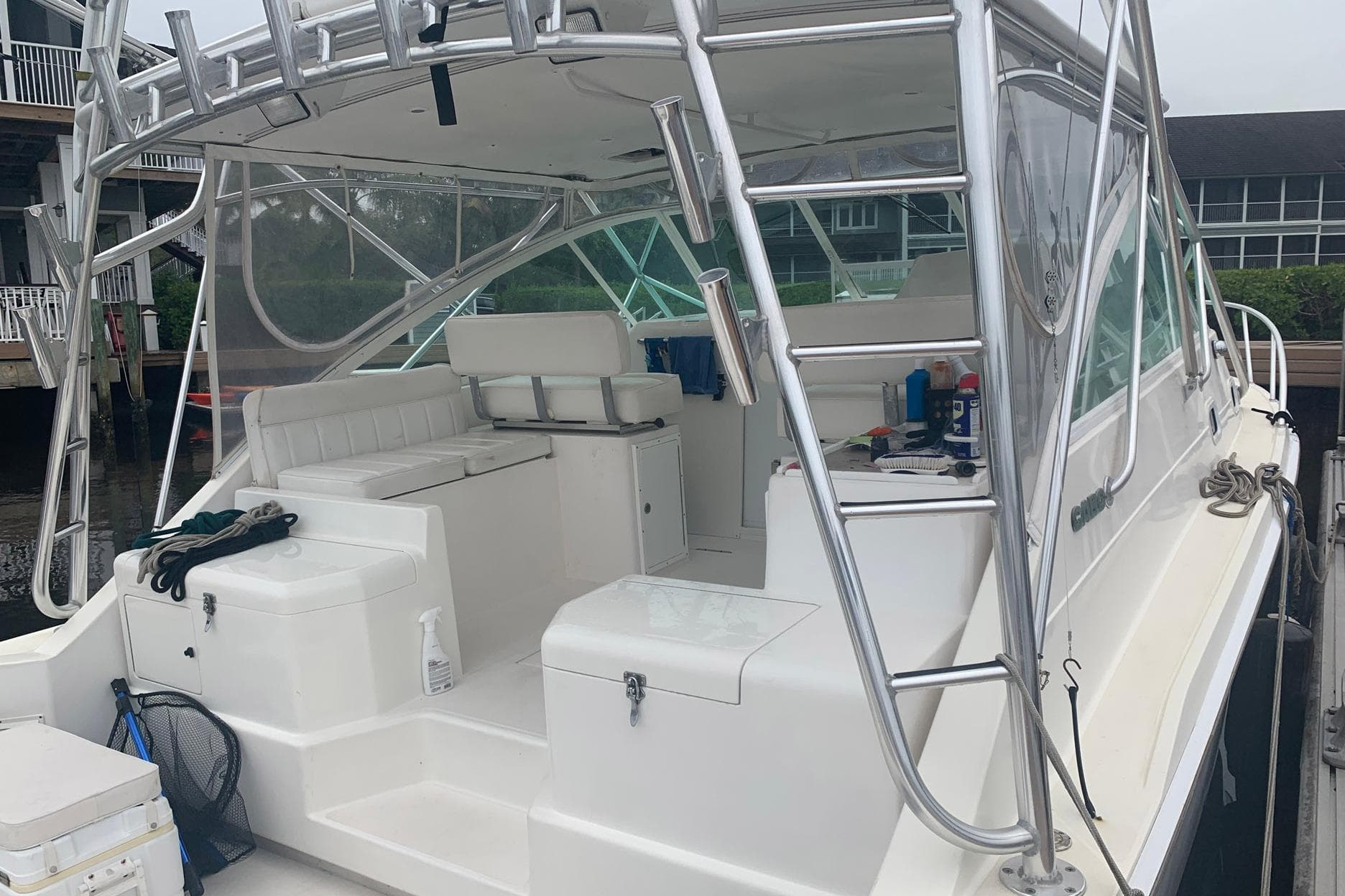 2002 Cabo 35 Express boat with white seating and stainless steel ladder in a marina.