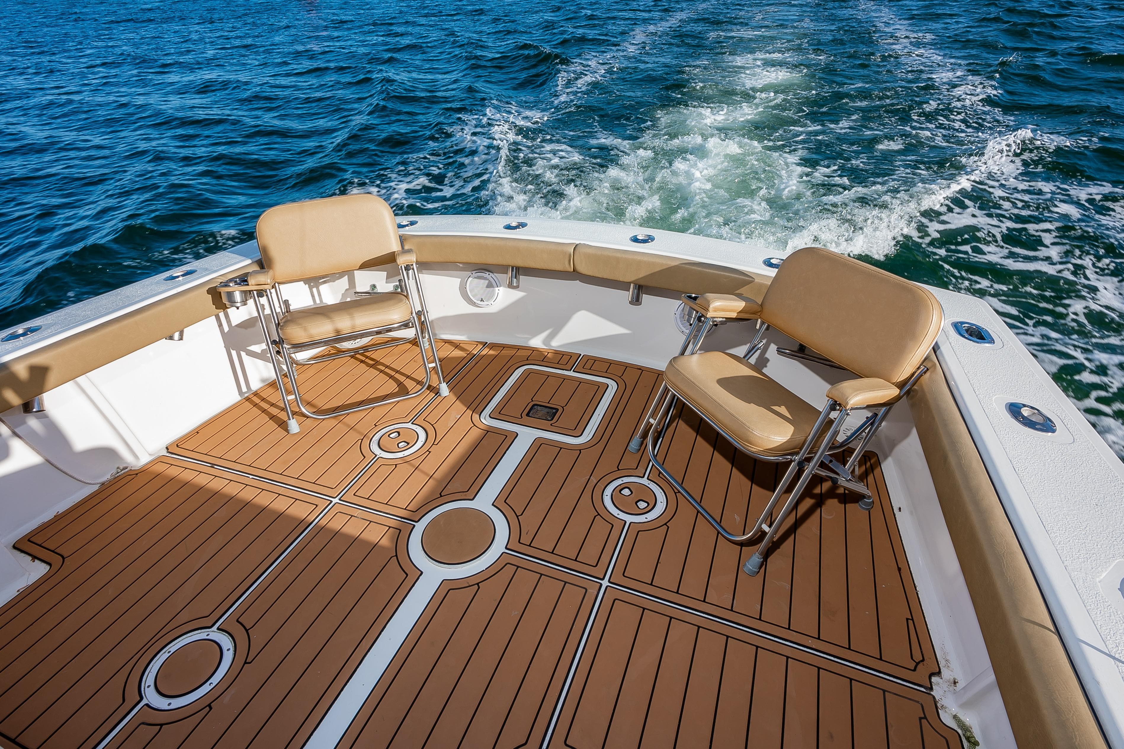 1987 Custom Carolina Island Boatworks 34 Express, spacious deck with chairs, cruising on water.
