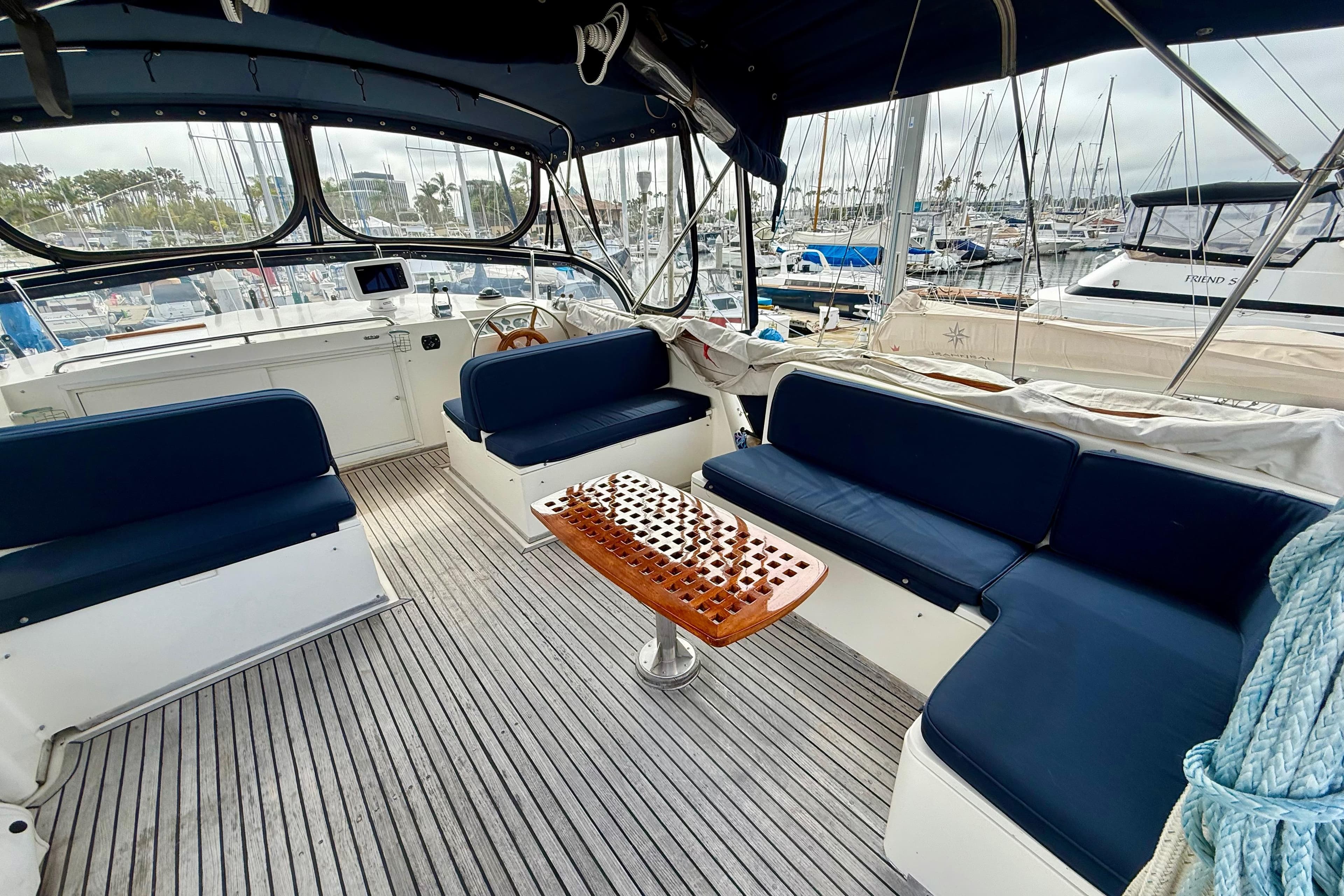 Spacious cockpit of 1992 Grand Banks 46 Classic yacht with blue seating and wooden table.