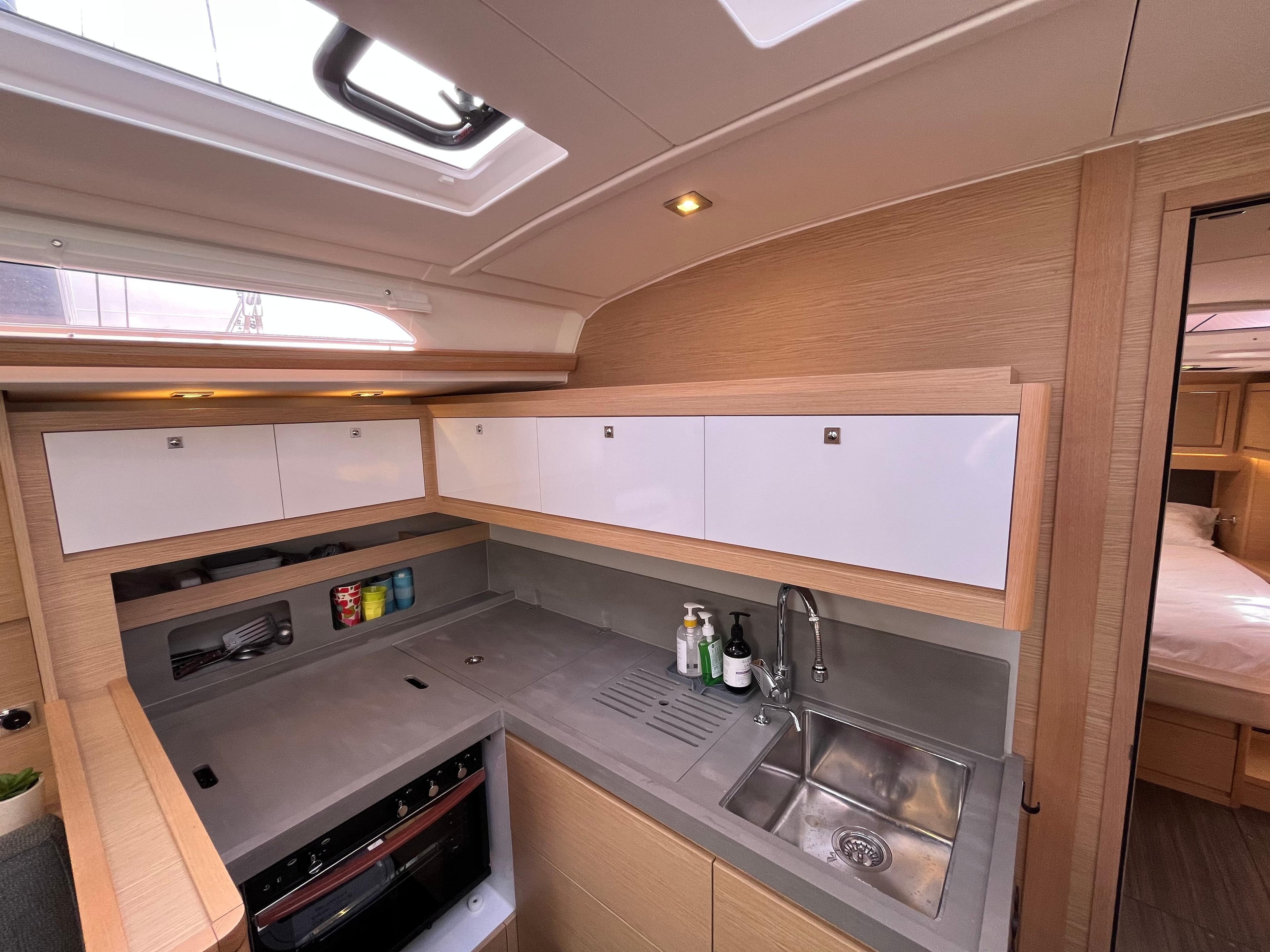 Modern kitchen interior of 2023 Dufour 470 yacht, featuring sleek cabinetry and stainless steel sink.