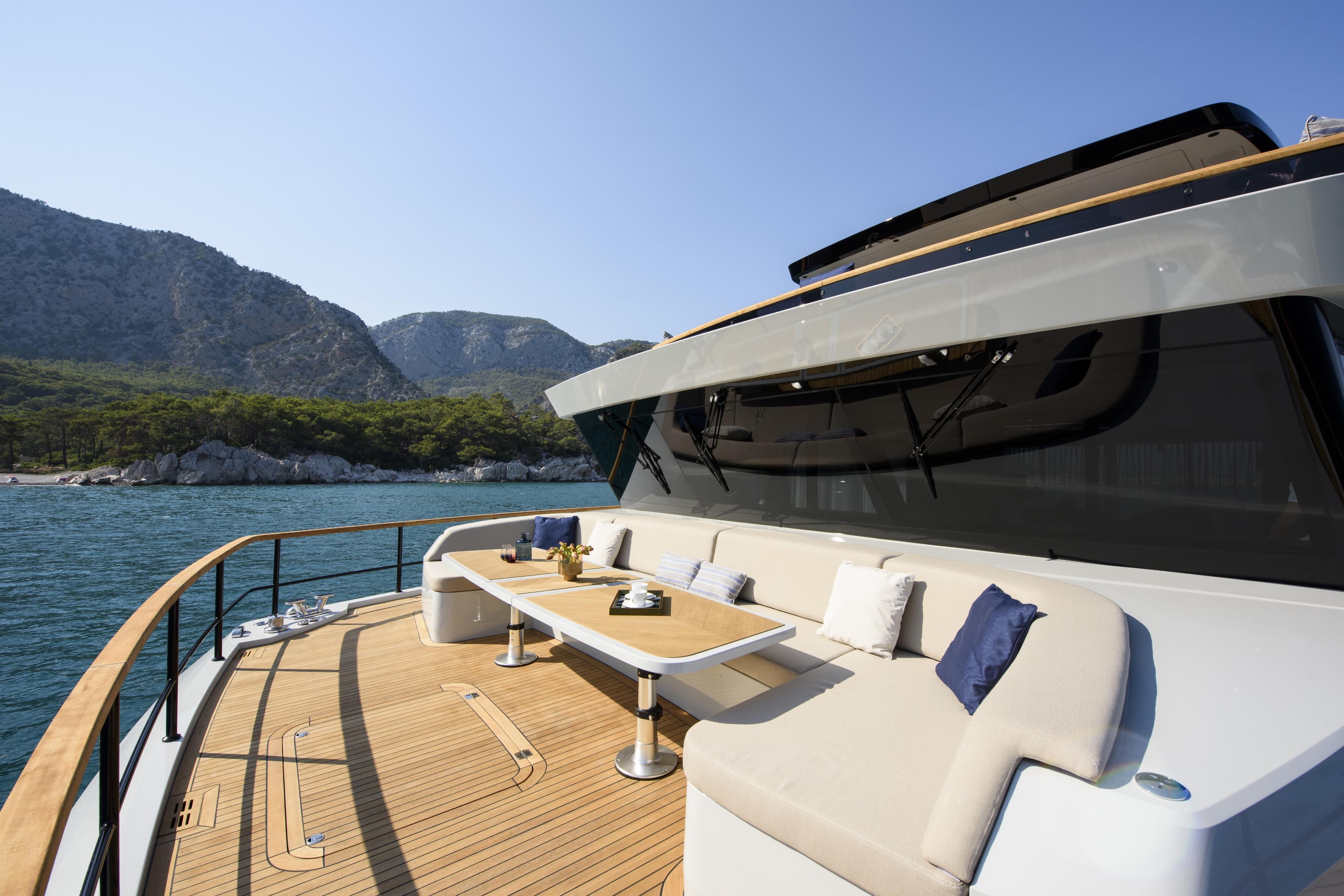 Luxurious 2027 Lazzara LPC 300 yacht deck with elegant seating and scenic mountain backdrop.