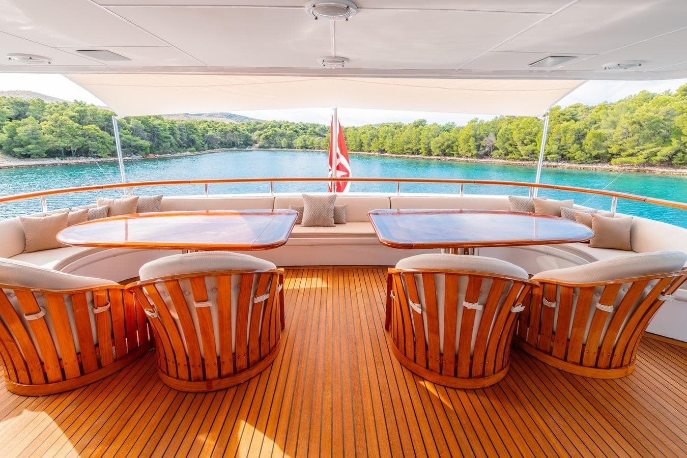 Luxurious 1983 Feadship 55 yacht deck with elegant wooden seating and scenic ocean view.