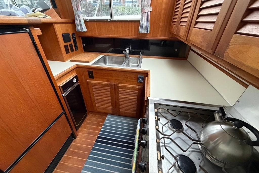 1994 Tollycraft 45 Cockpit Motor Yacht kitchen with wood cabinetry and stainless steel appliances.