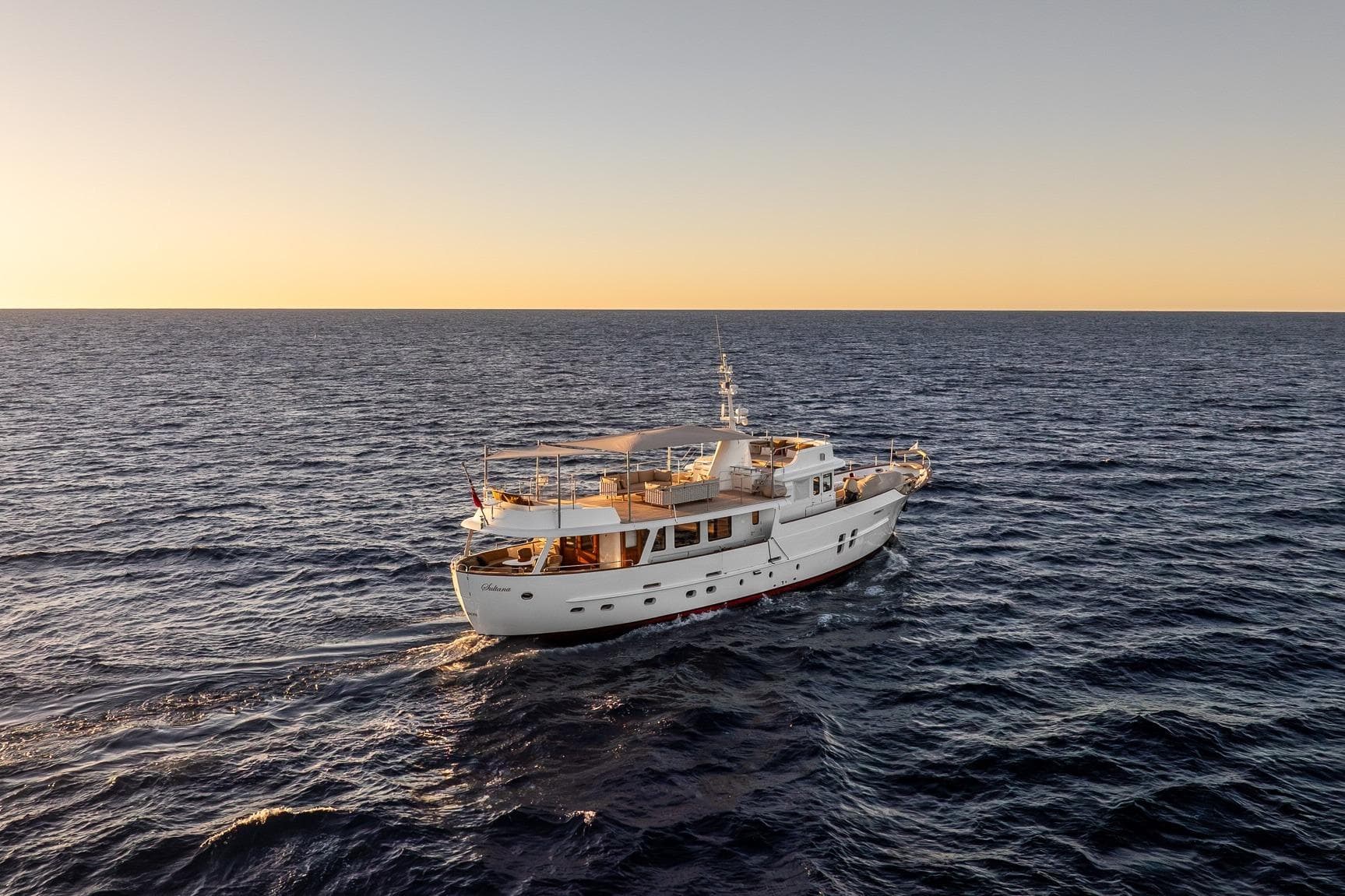 Vintage 1969 Feadship 25.8m yacht cruising at sunset on open sea.
