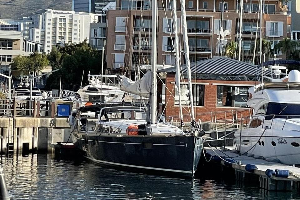 Beneteau Sense 55 yacht docked at marina, surrounded by modern buildings, 2015 model.