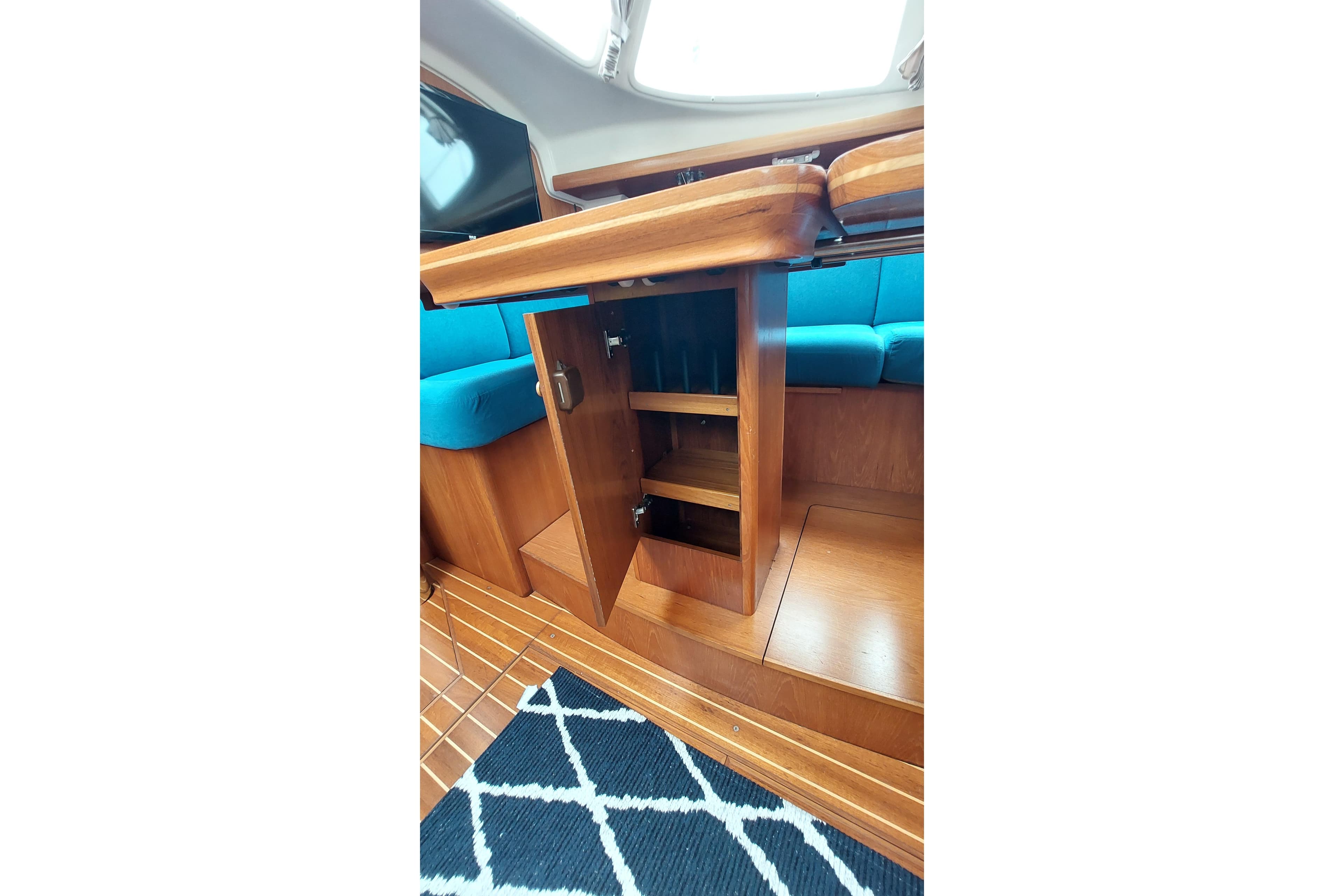 Interior of 2002 Jeanneau Sun Odyssey 43 DS with wooden cabinetry and blue seating.