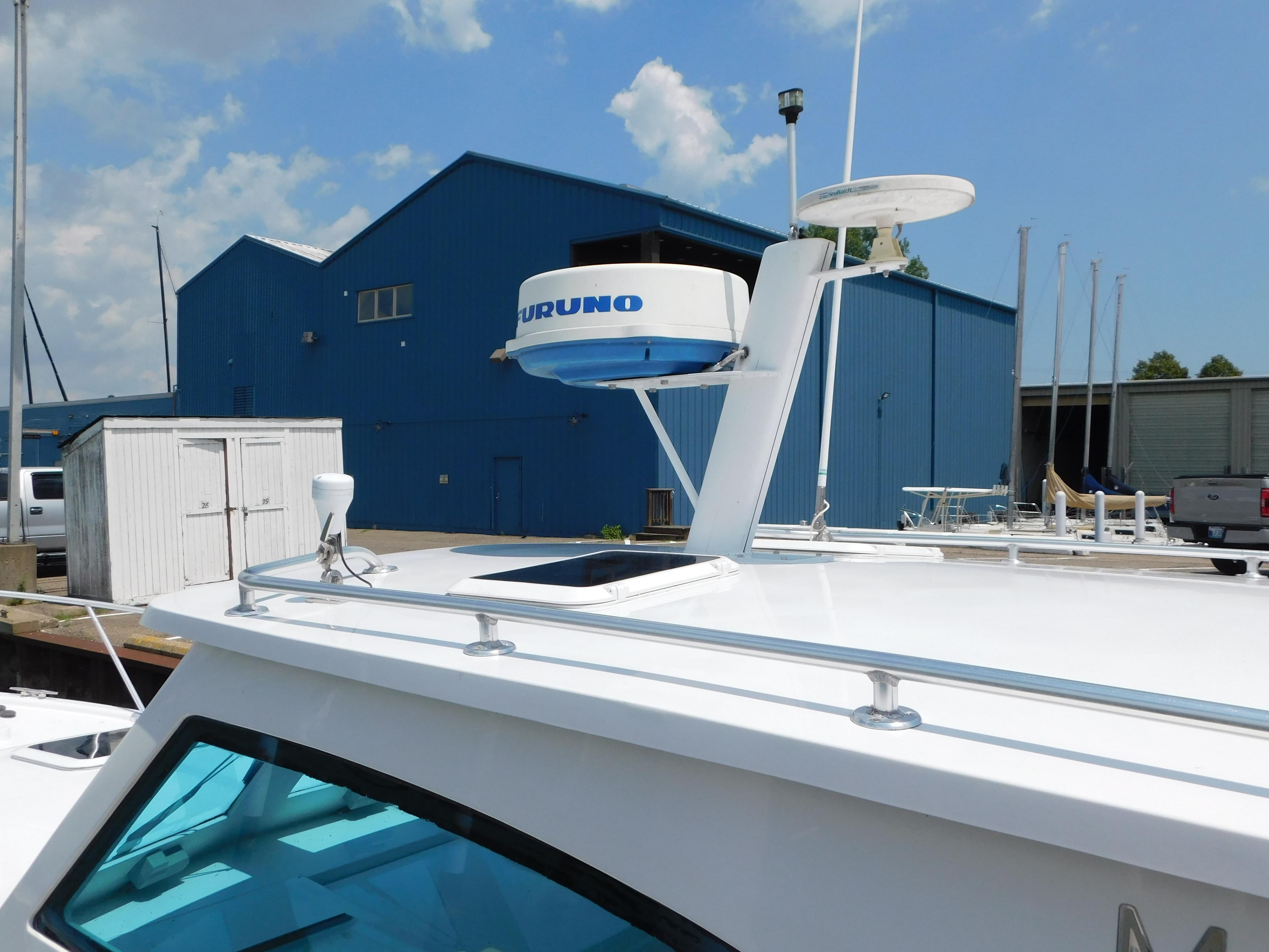 1999 Mainship Pilot 30 boat docked near blue industrial buildings under a cloudy sky.