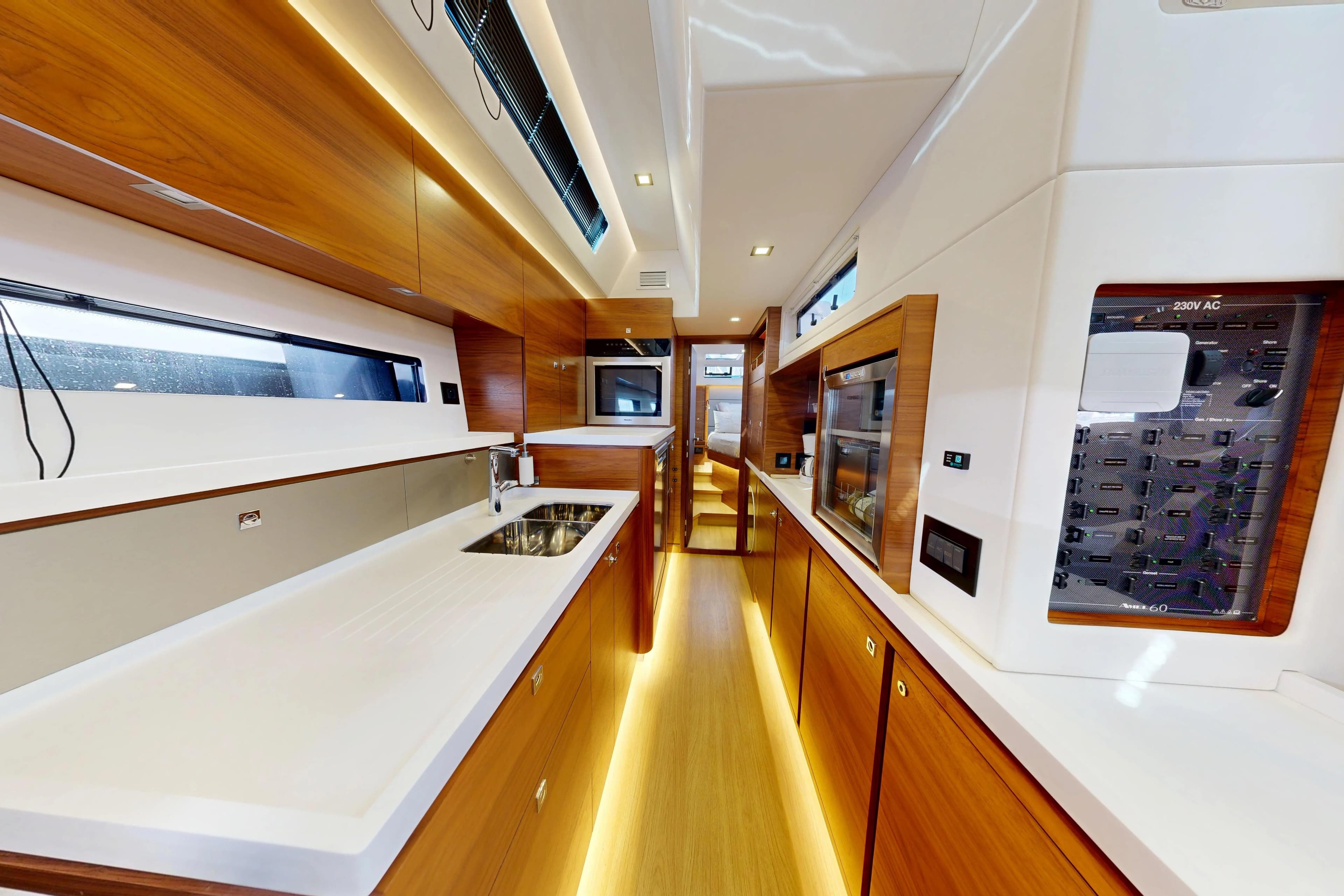 Luxurious interior of 2024 Amel 60 yacht, featuring modern kitchen and sleek wood finishes.