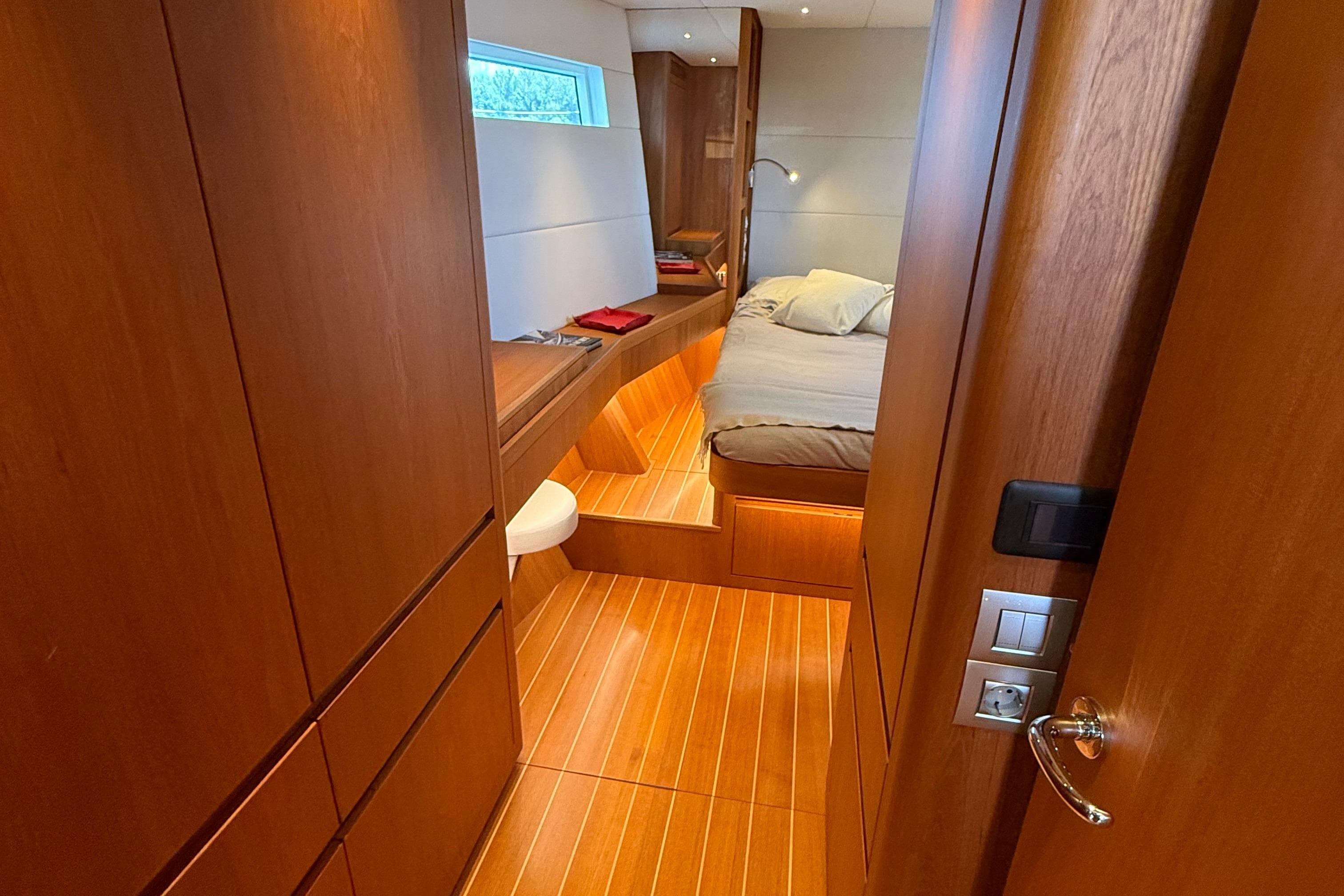Luxurious cabin interior of 2018 Contest 67CS yacht with wooden finishes and cozy bed.